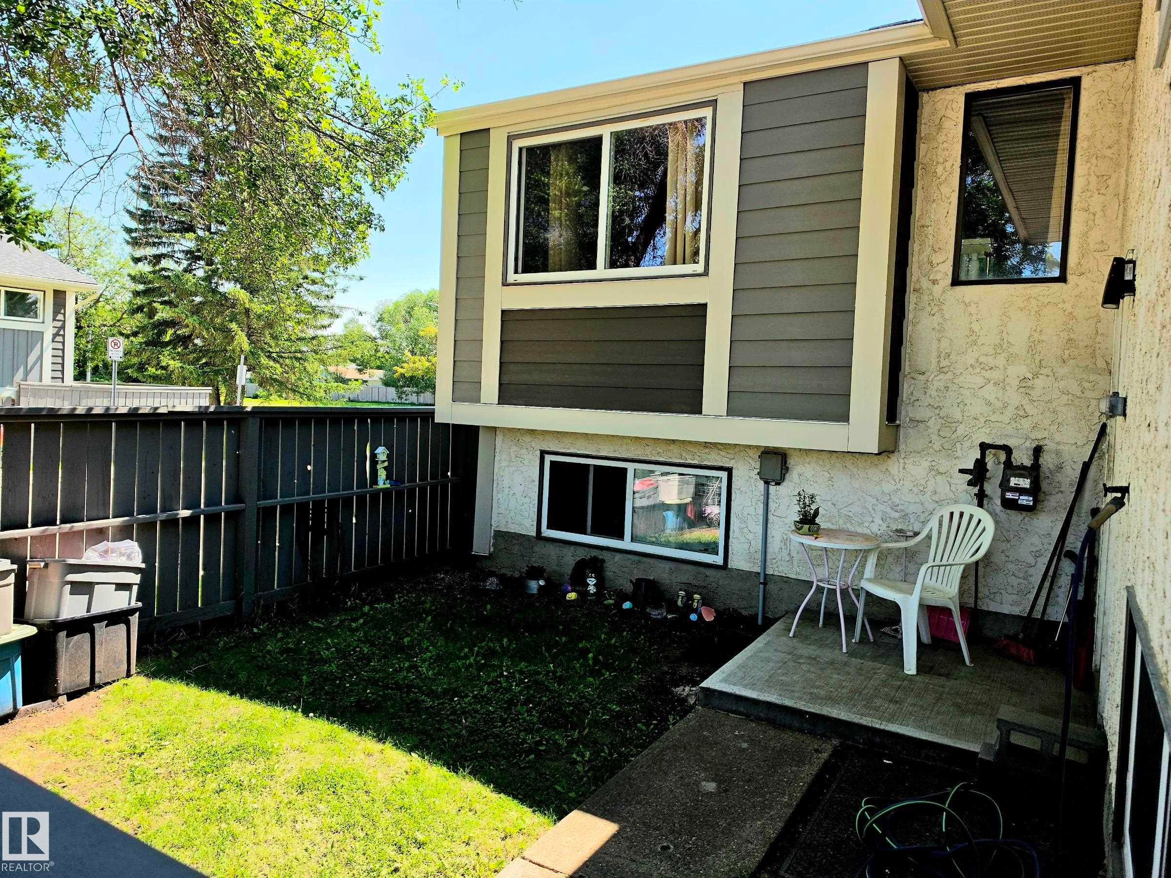 Exterior property featuring stucco and horizontal siding, multiple windows, a small concrete patio, and a fenced grassy area - 600 Willow Crest Nw, Edmonton, AB