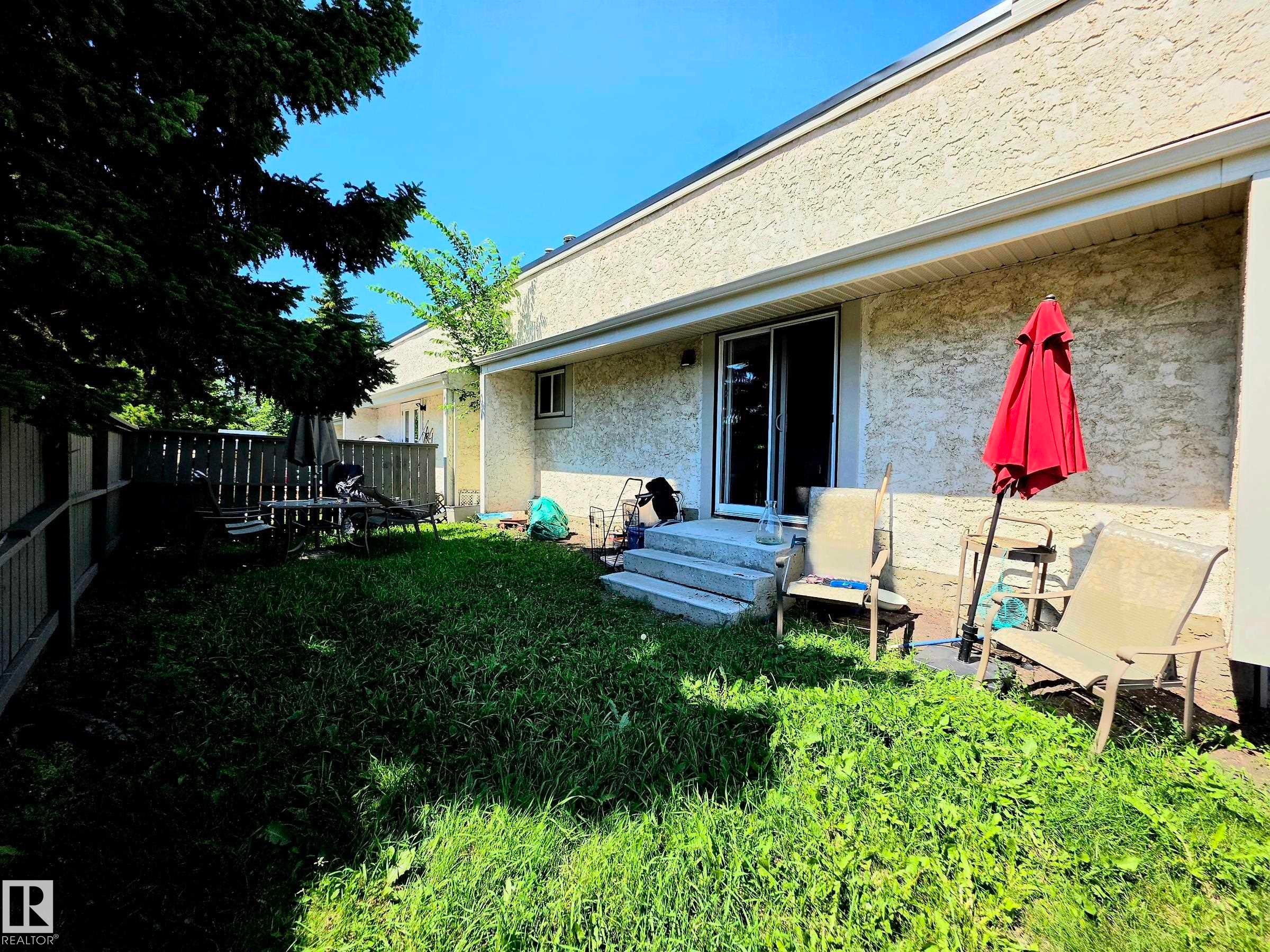 South backing rear exterior featuring stucco siding, a concrete patio, and mature perimeter trees - 600 Willow Crest Nw, Edmonton, AB