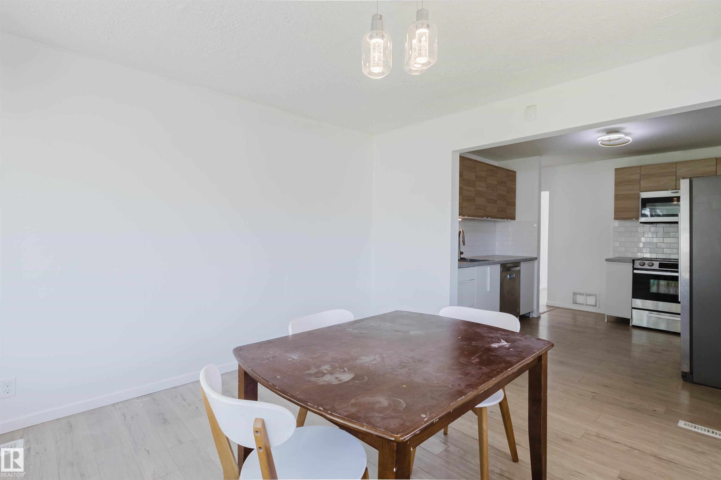 Open concept living space featuring wood-finish flooring, recessed lighting, and a modern kitchen with stainless steel appliances, light wood-finish cabinetry, and white subway tile backsplash - 9606 163 Street Nw, Edmonton, AB