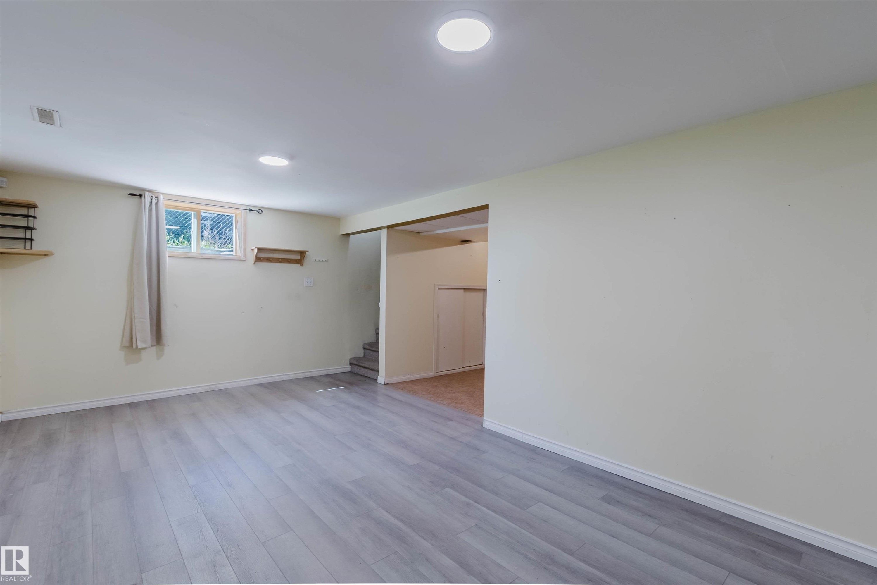Spacious room featuring wood-finish flooring, recessed lighting, and a window providing natural light - 9606 163 Street Nw, Edmonton, AB