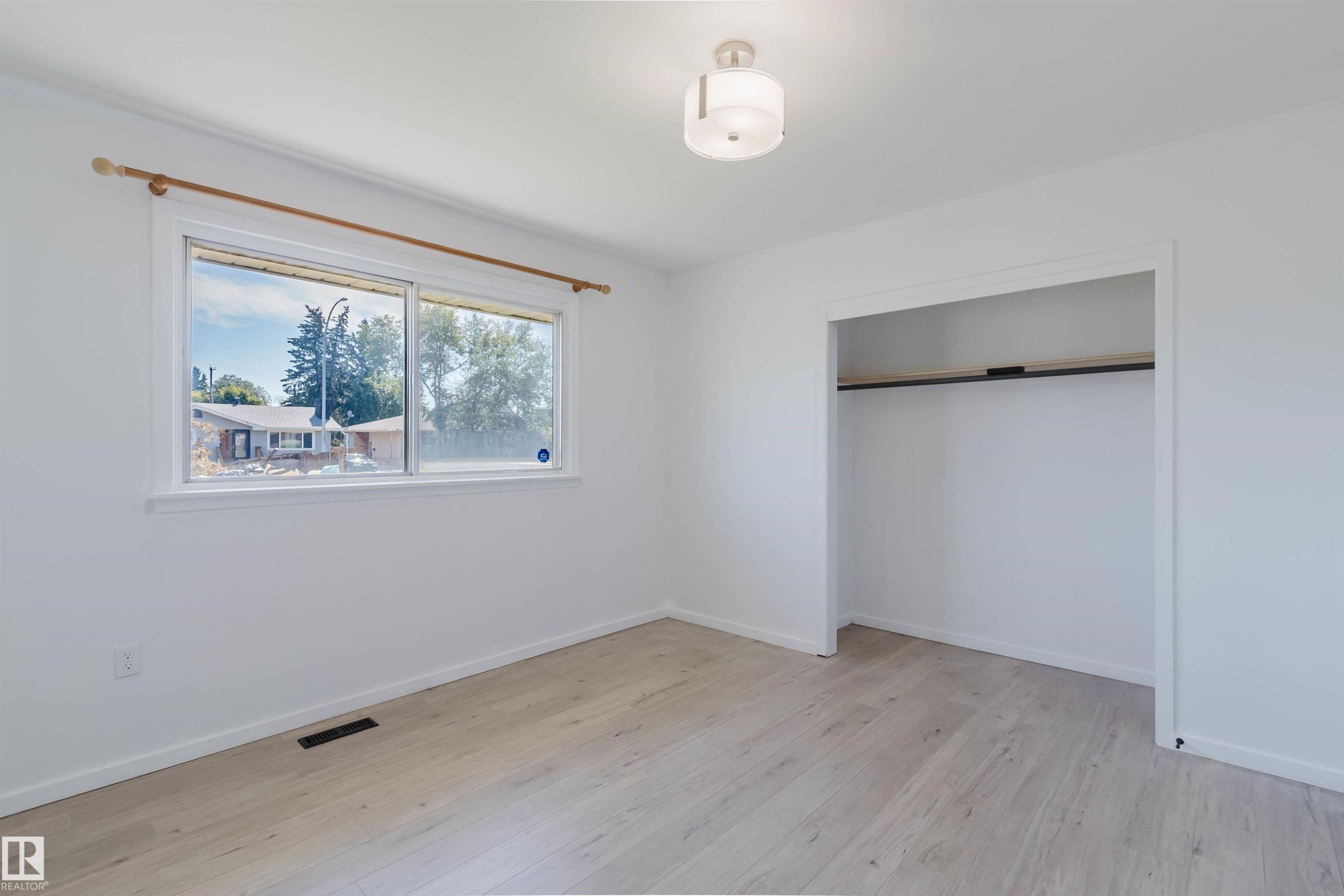 Room featuring light wood-finish flooring, white walls, and a contemporary semi-flush mount ceiling fixture - 9606 163 Street Nw, Edmonton, AB