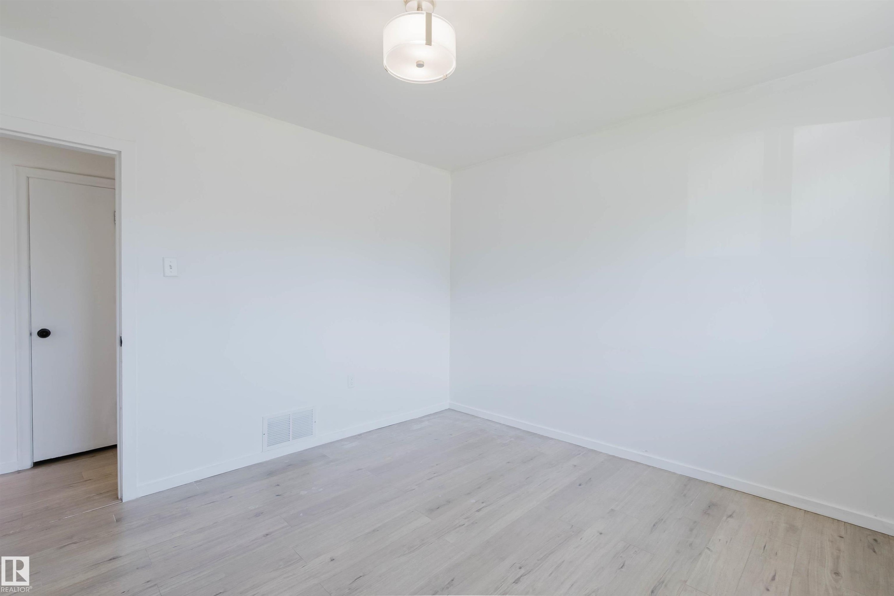 Interior room featuring light wood-finish flooring, white walls, and a contemporary flush-mount ceiling light - 9606 163 Street Nw, Edmonton, AB
