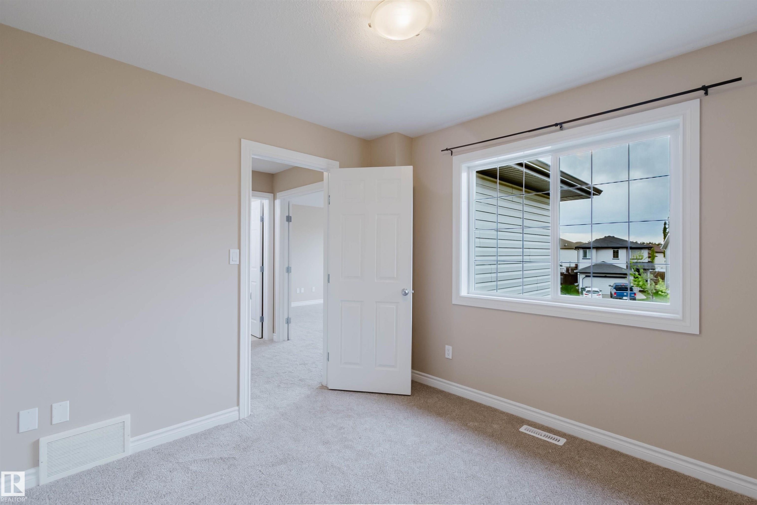 Carpeted room with a large window featuring white trim and grids - 1919 Hammond Place, Edmonton, AB