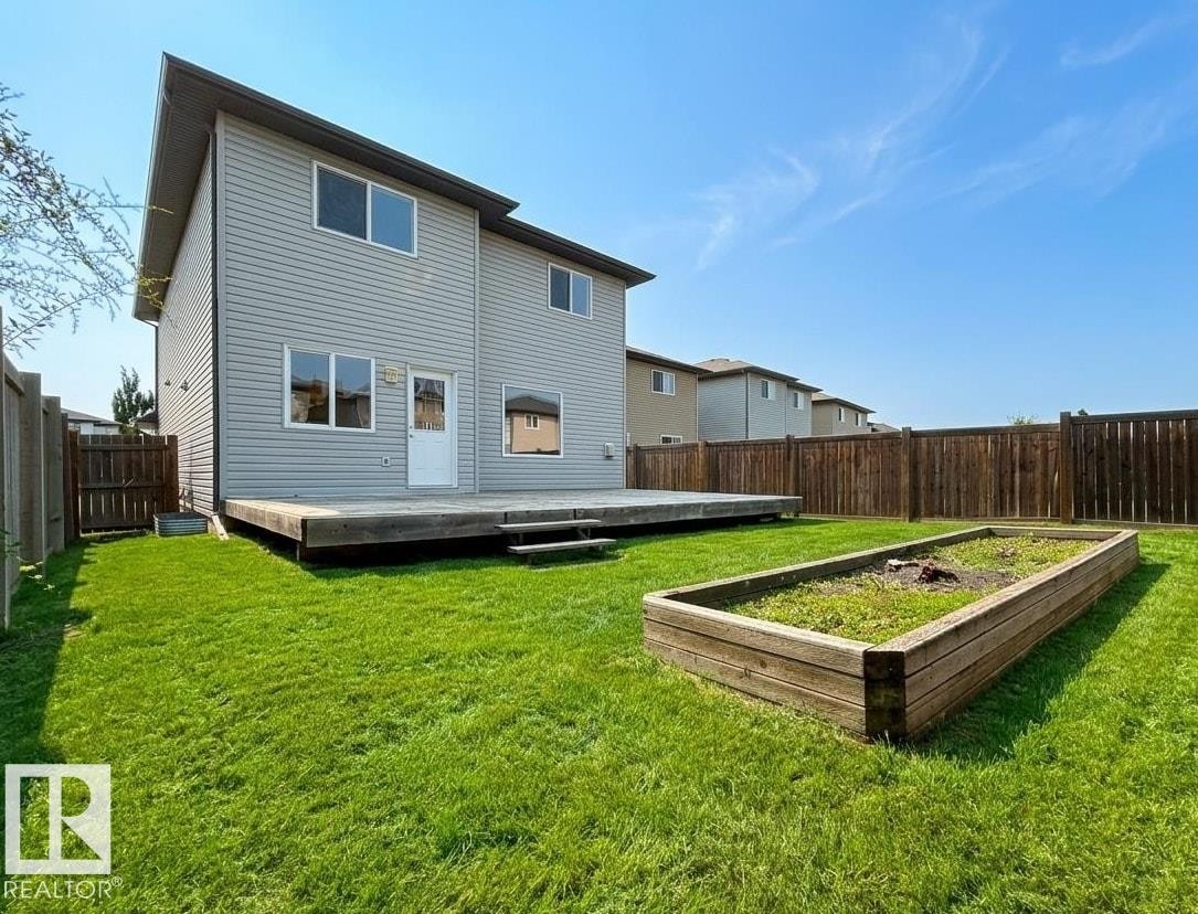 Expansive backyard featuring a large wooden deck, a dedicated garden bed, and a full perimeter wood fence - 1919 Hammond Place, Edmonton, AB