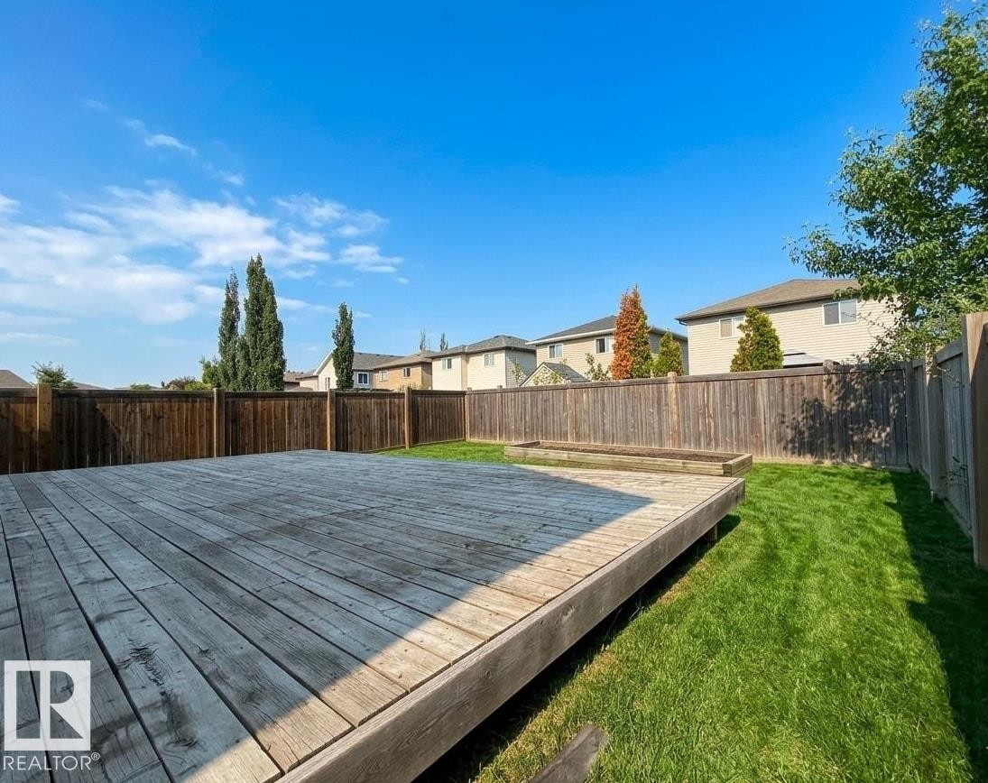Spacious backyard featuring a large wooden deck, perimeter fencing, and a grassy area - 1919 Hammond Place, Edmonton, AB