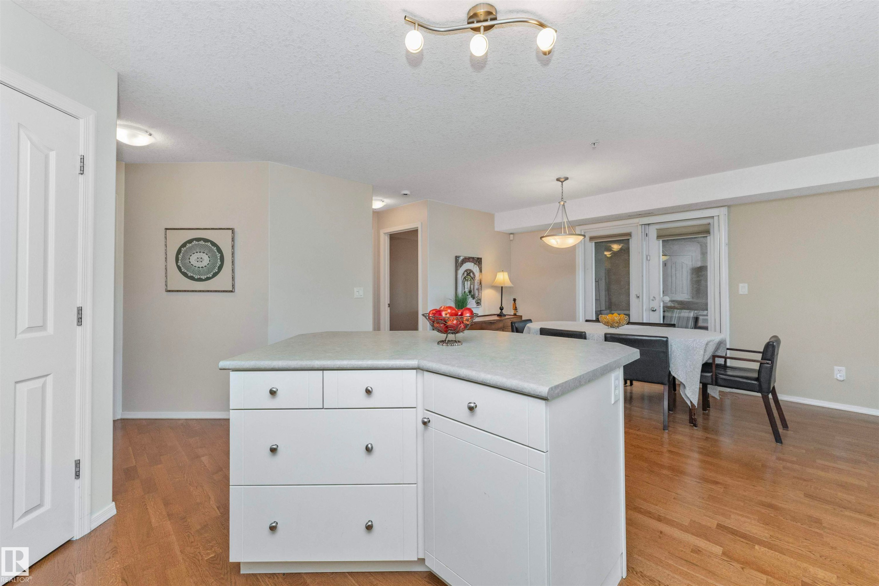 Kitchen island with white cabinetry and light-toned countertop - #130 9008 99 Av Nw Nw, Edmonton, AB