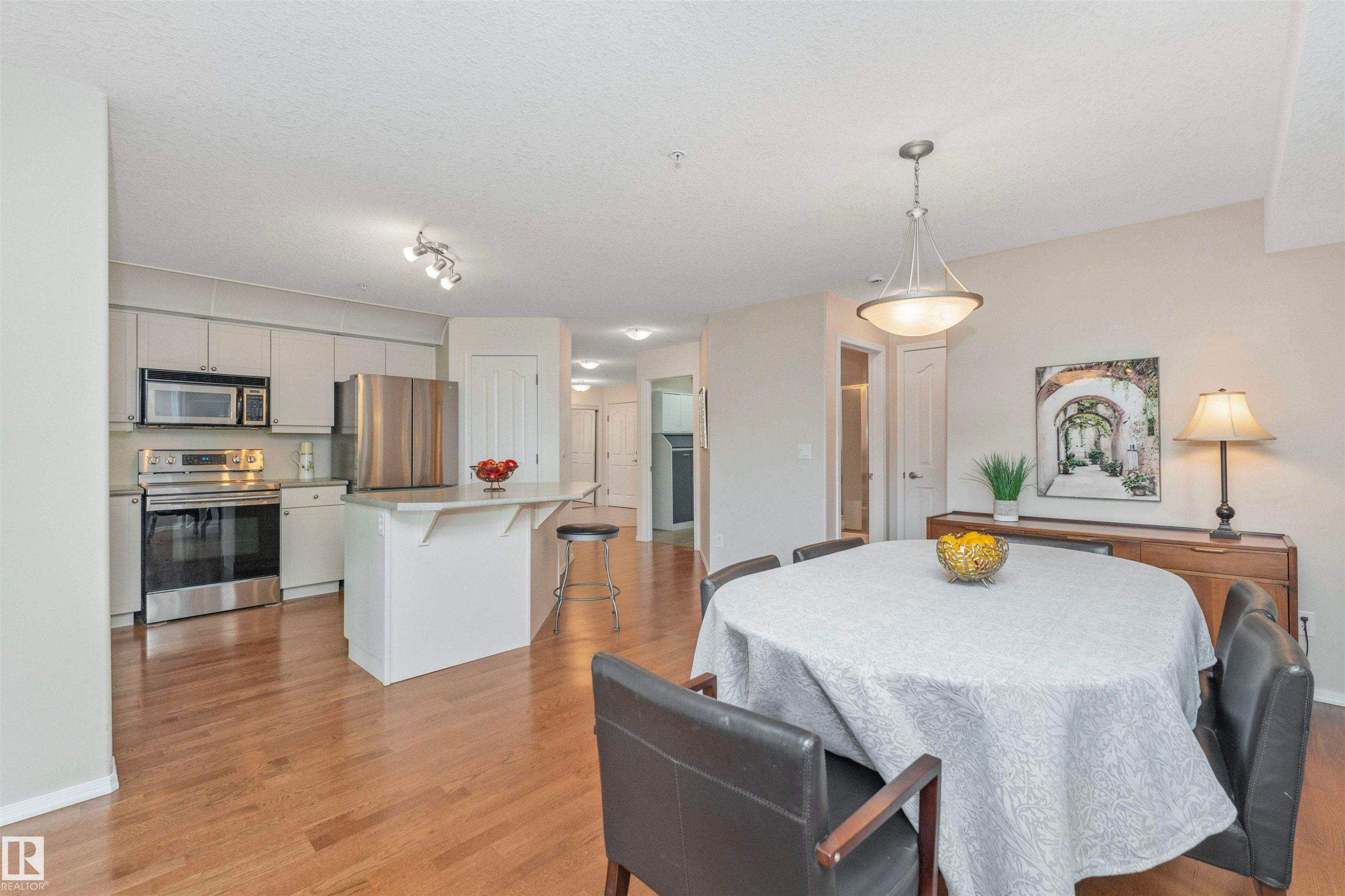 Open-concept kitchen and dining area featuring wood-finish flooring - #130 9008 99 Av Nw Nw, Edmonton, AB