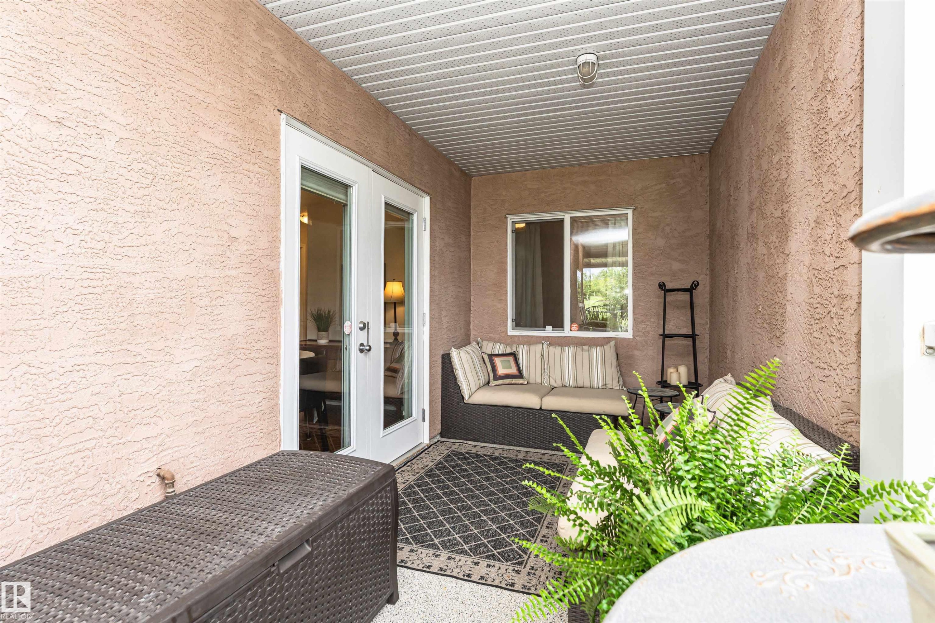 Covered patio with textured exterior walls and a white paneled ceiling - #130 9008 99 Av Nw Nw, Edmonton, AB