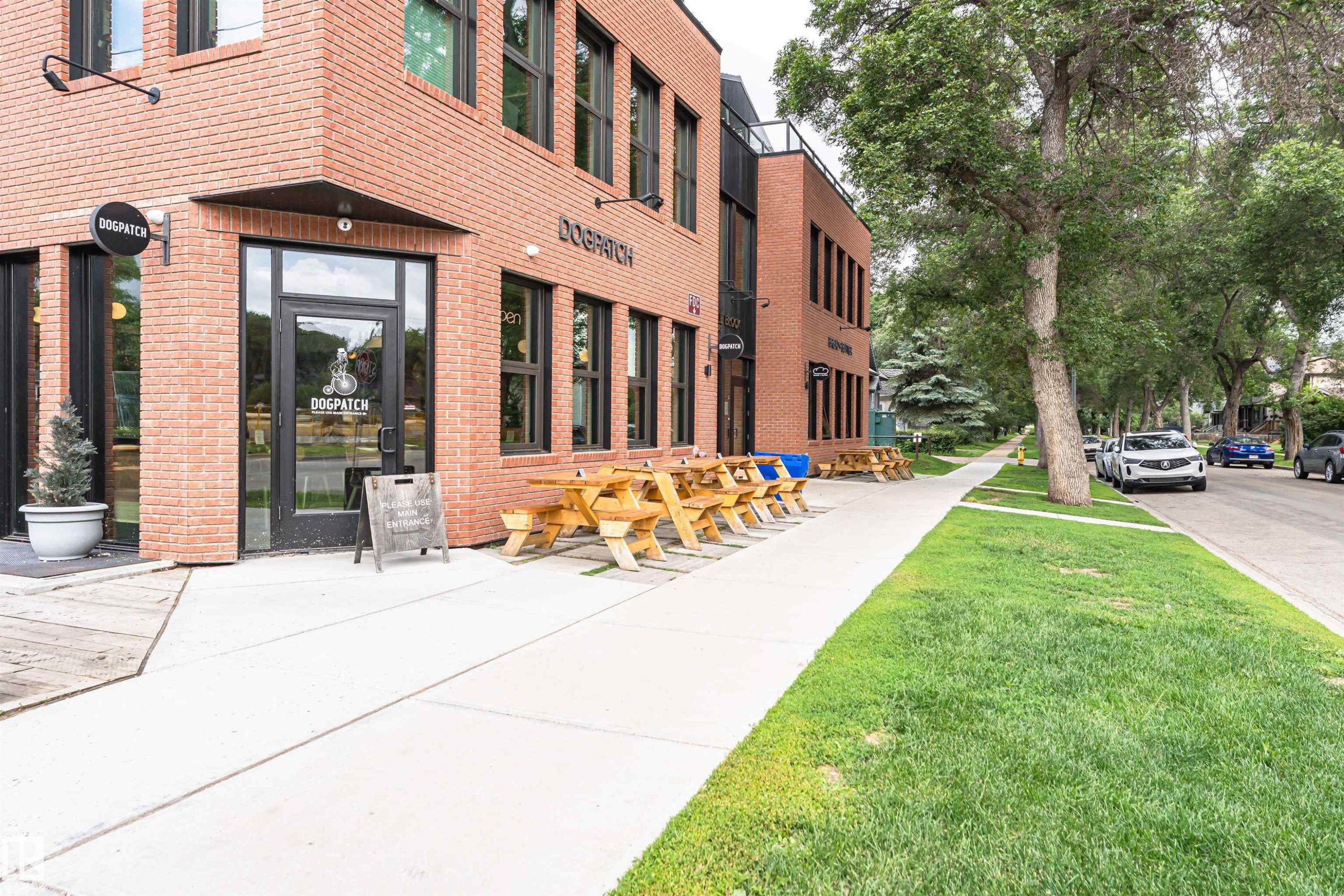 Brick facade building featuring multiple large windows and an entryway with a prominent glass door - #130 9008 99 Av Nw Nw, Edmonton, AB