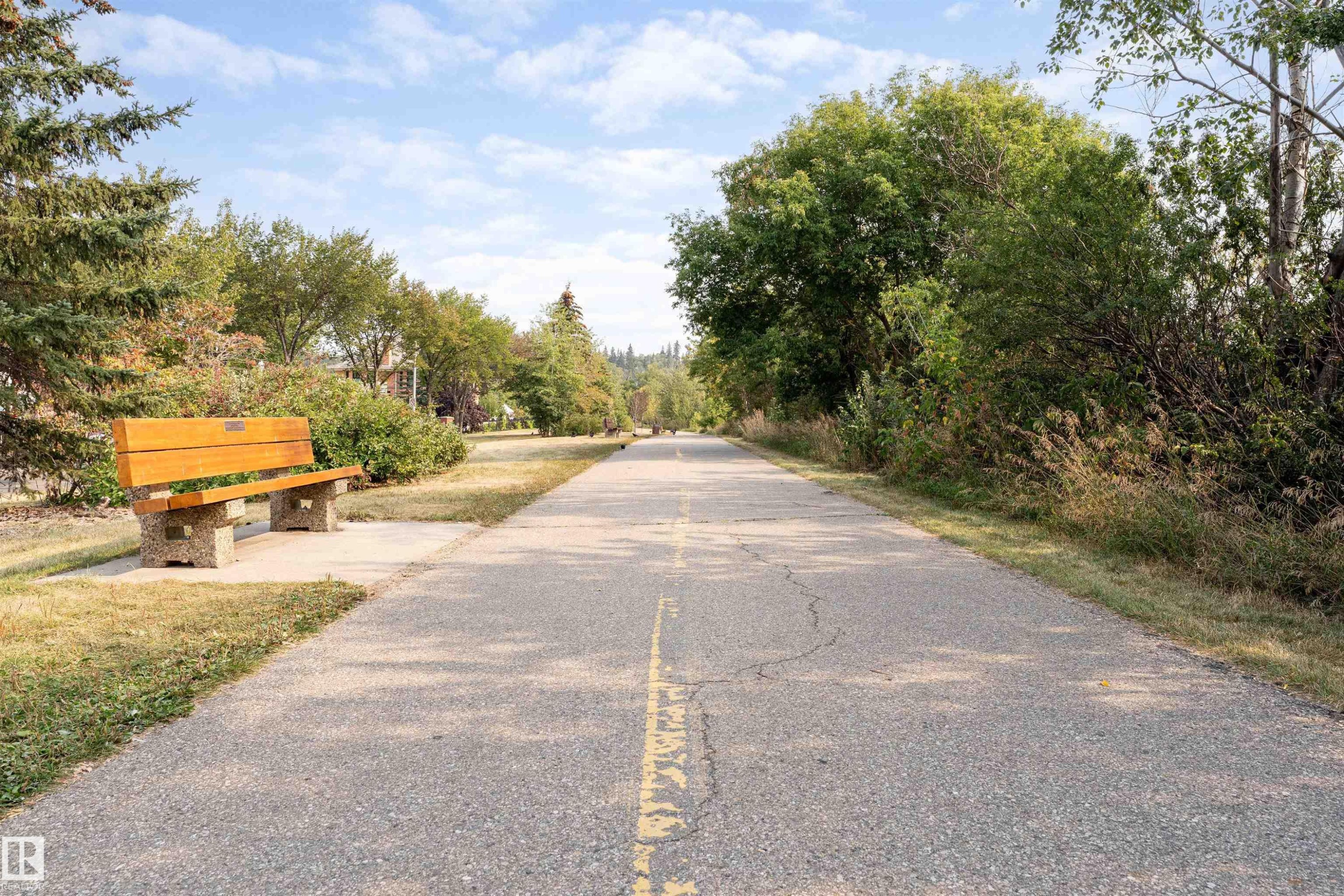 Paved recreational pathway featuring a concrete and wood bench - #130 9008 99 Av Nw Nw, Edmonton, AB