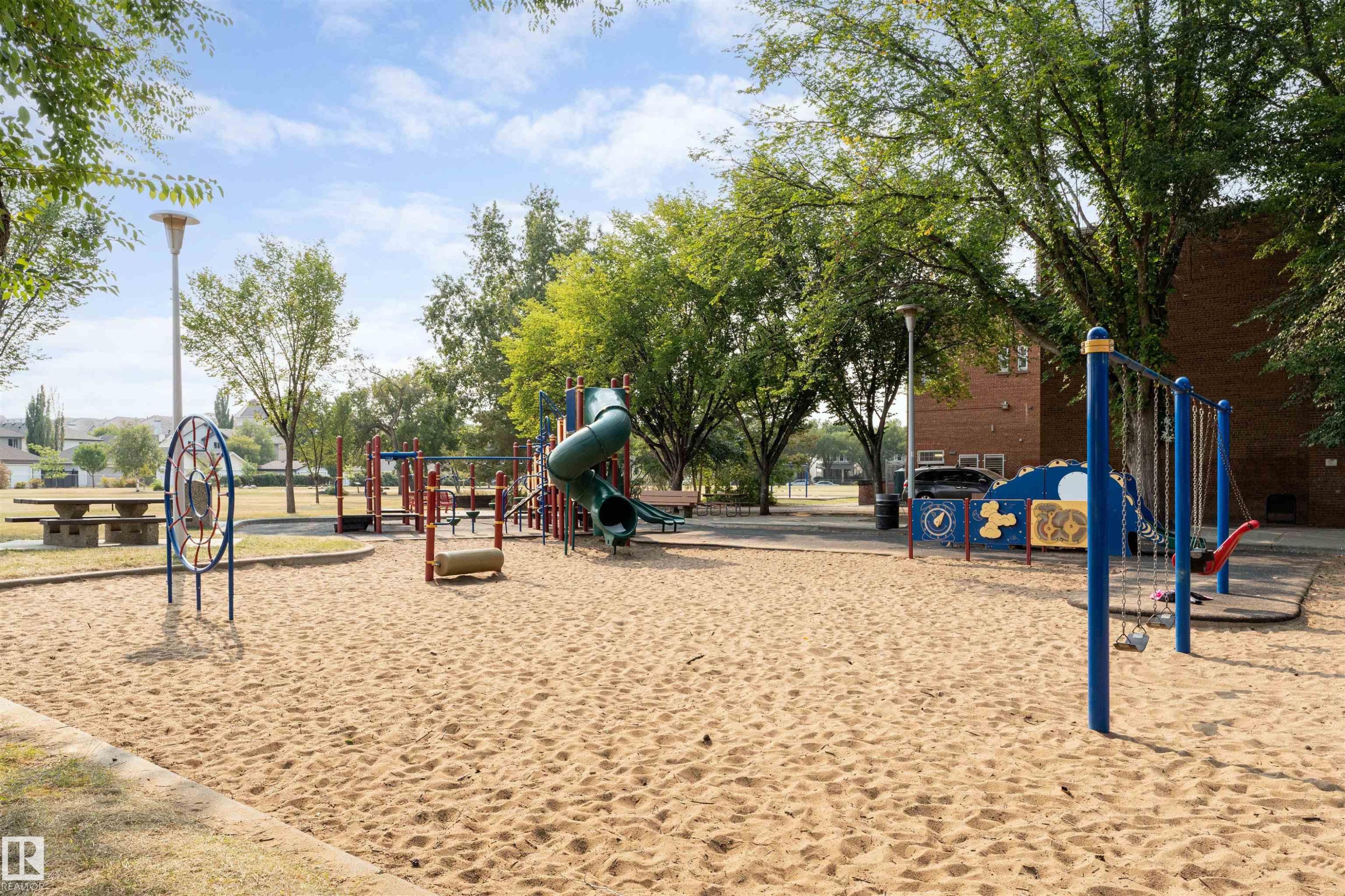 Community park featuring a sand play area with a slide structure and swings - #130 9008 99 Av Nw Nw, Edmonton, AB