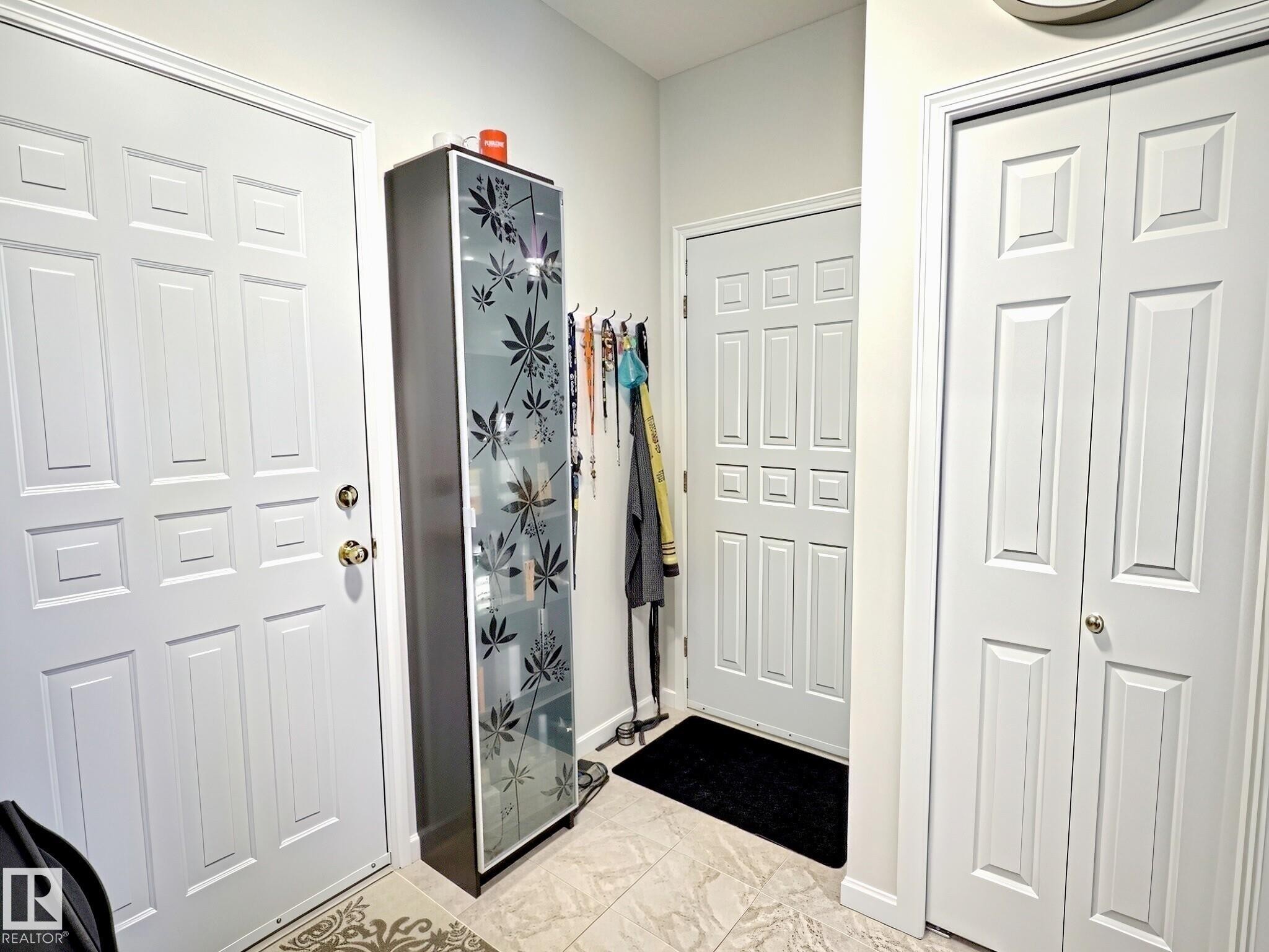 Foyer featuring white panel doors, neutral wall paint, and tile flooring - 17 10 Blackburn Drive, Edmonton, AB