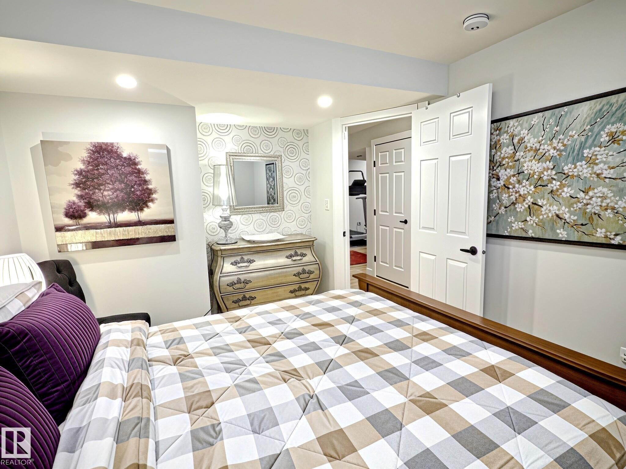 Recessed lighting illuminates this room featuring a patterned accent wall and a white multi-panel door with black hardware - 17 10 Blackburn Drive, Edmonton, AB