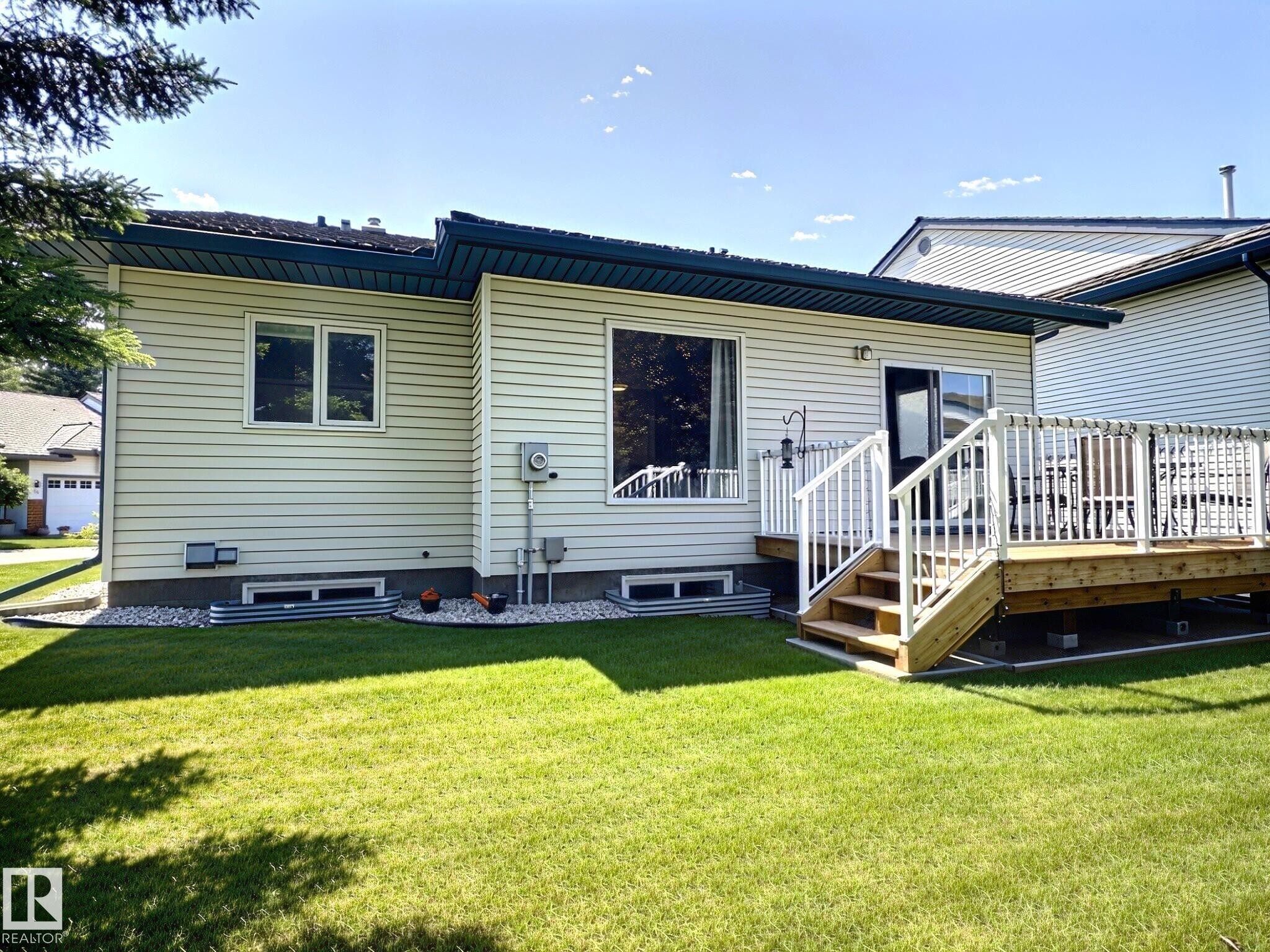 Expansive grass lawn with a wooden deck and white railings - 17 10 Blackburn Drive, Edmonton, AB