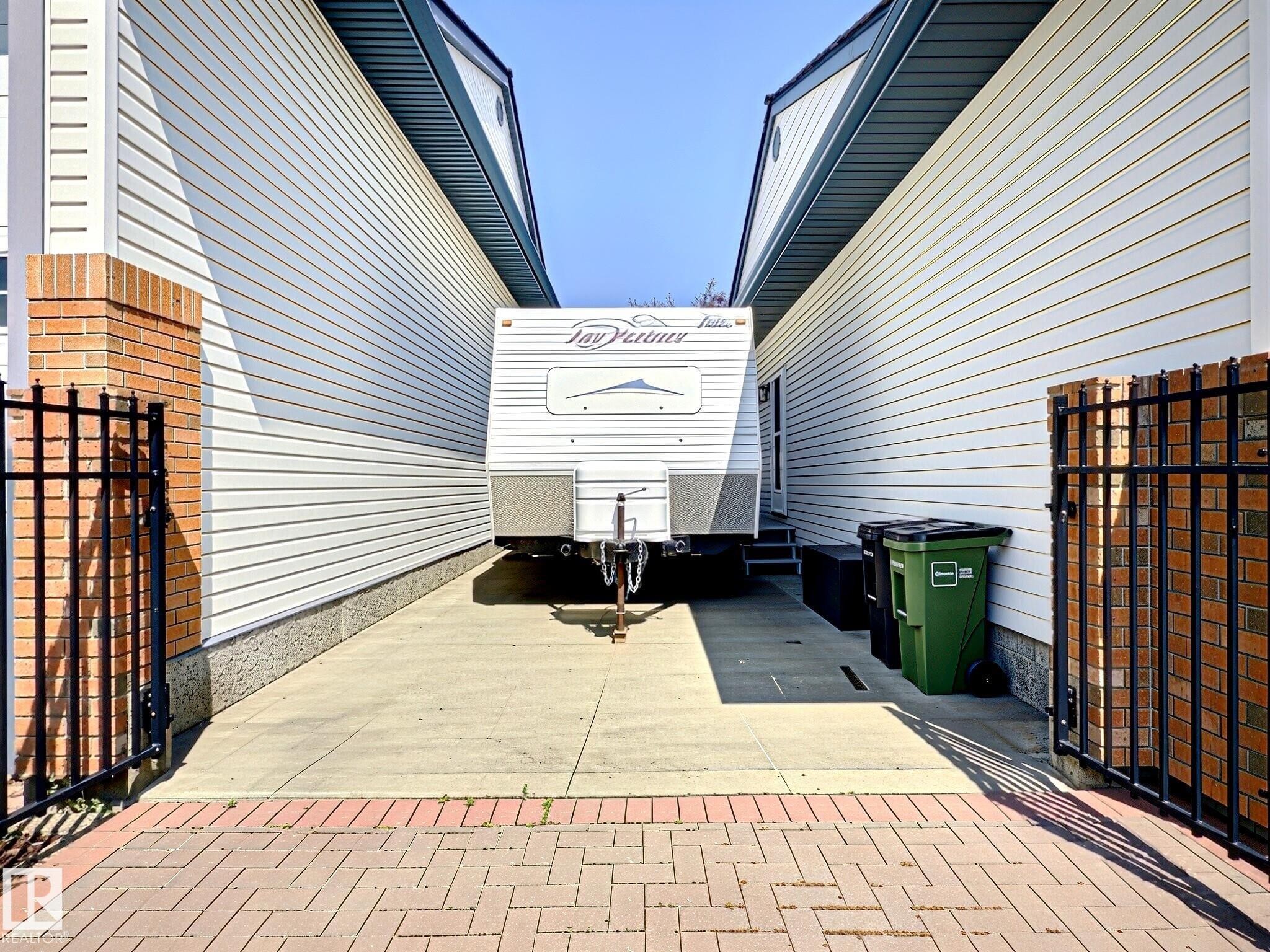 Paved access area featuring a brick paver entrance, concrete drive, and white horizontal siding on the exterior walls - 17 10 Blackburn Drive, Edmonton, AB