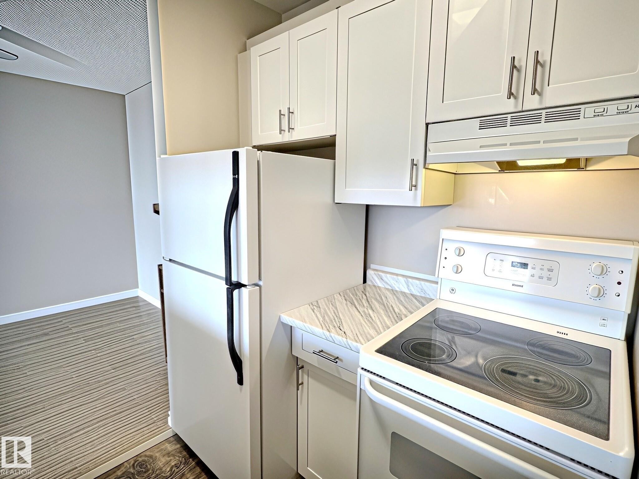 Kitchen featuring white cabinetry, white appliances, and marble-patterned countertops - 1105 11007 83 Avenue, Edmonton, AB