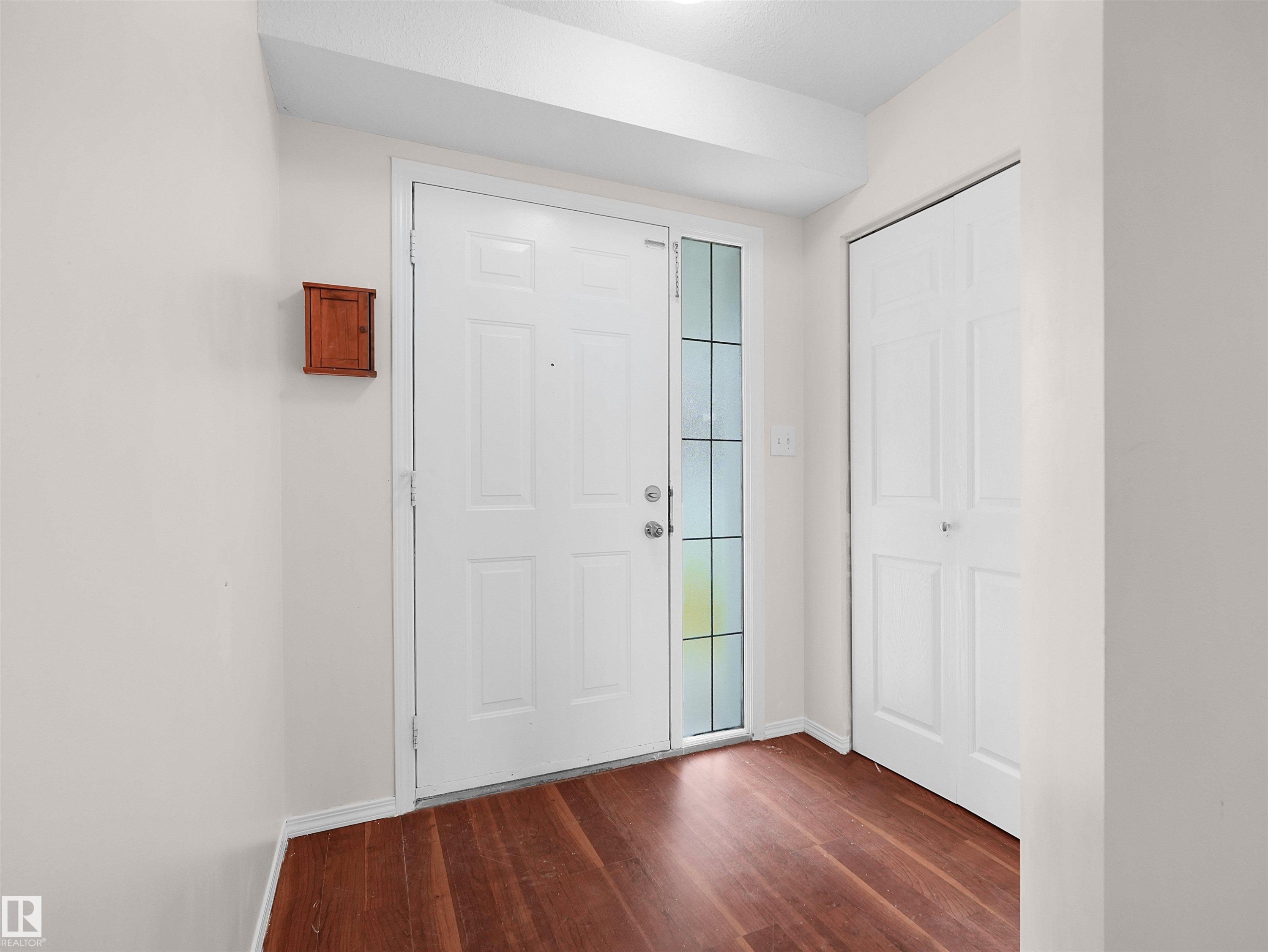 Entryway featuring a paneled white door with a sidelight, wood-finish flooring, and white walls - 16106 131A Street Nw, Edmonton, AB - Indoor Photo Showing Other Room
