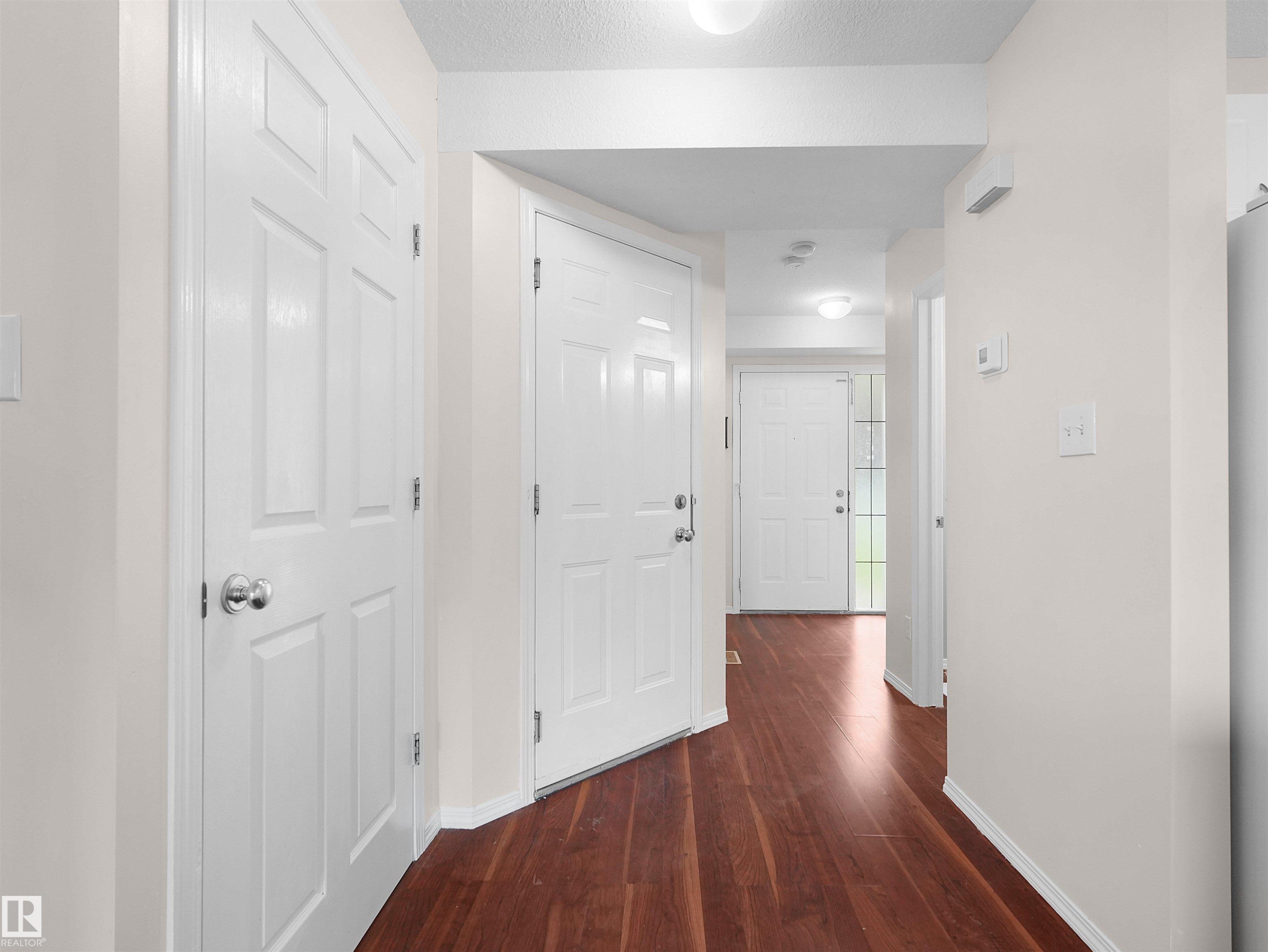 Entryway featuring wood-finish flooring, white paneled doors, and light-toned walls - 16106 131A Street Nw, Edmonton, AB - Indoor Photo Showing Other Room
