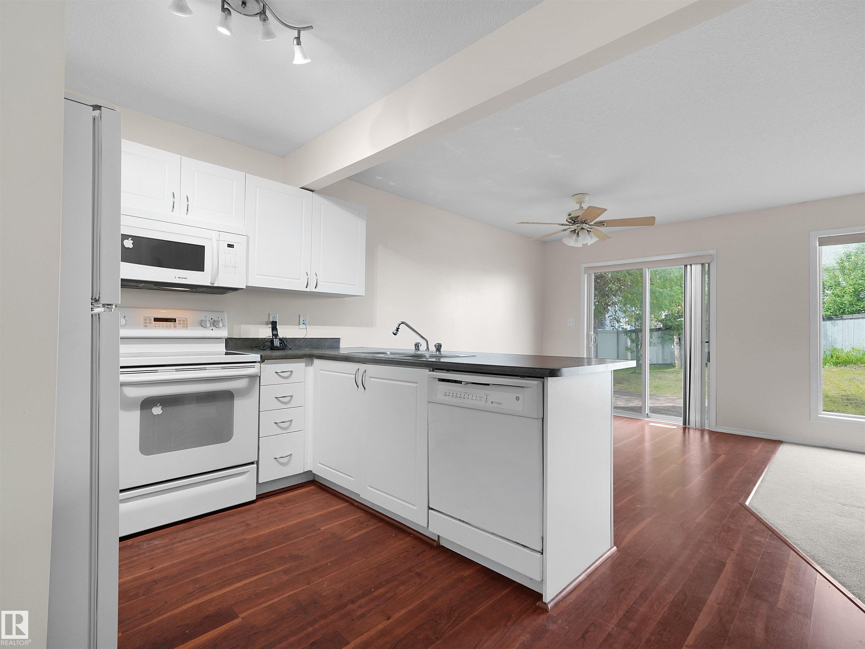 Kitchen featuring white cabinetry, dark countertops, and stainless steel appliances - 16106 131A Street Nw, Edmonton, AB - Indoor Photo Showing Kitchen
