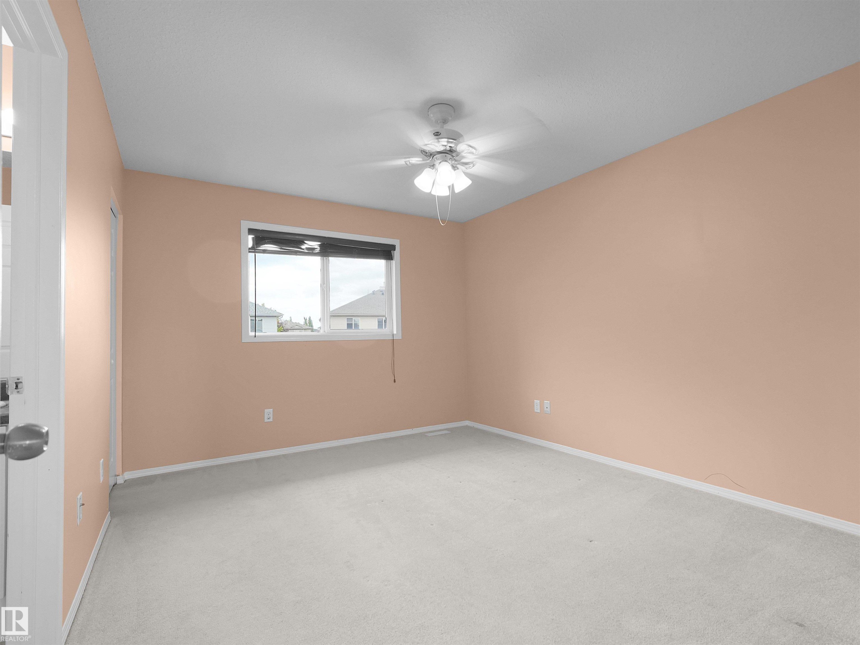 Carpeted room featuring a ceiling fan with integrated lighting, a window with a roller shade, and light-colored walls - 16106 131A Street Nw, Edmonton, AB - Indoor Photo Showing Other Room