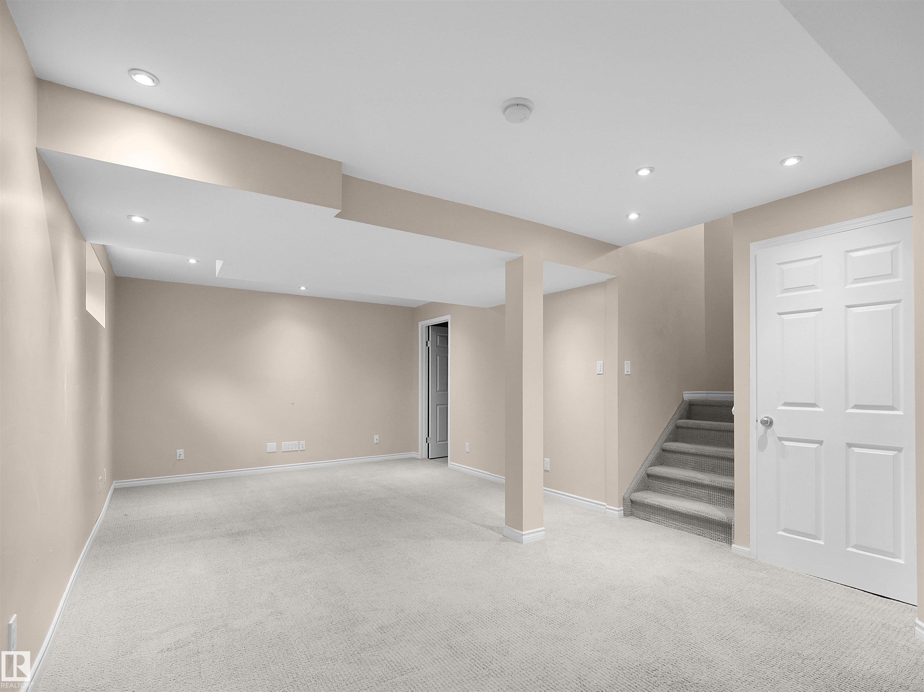 Carpeted lower-level room featuring recessed ceiling lighting, a staircase with carpeted treads, painted walls, and white trim - 16106 131A Street Nw, Edmonton, AB - Indoor