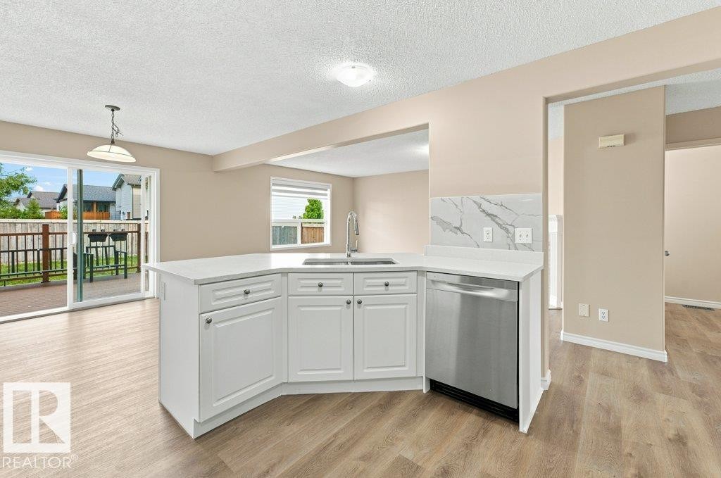 Kitchen island with white cabinetry, stainless steel dishwasher, and a white countertop - 2811 33 Street, Edmonton, AB