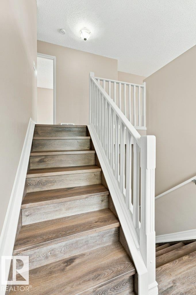 Staircase featuring wood-finish treads, white risers, and a white balustrade - 2811 33 Street, Edmonton, AB
