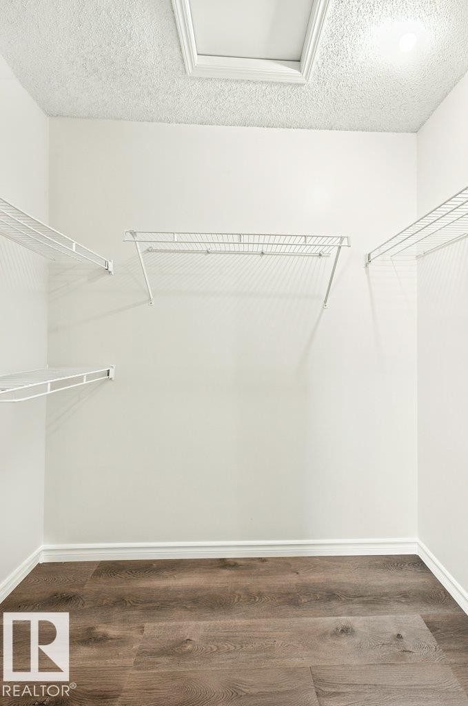 Walk-in closet with wood-finish flooring, white wire shelving, and a ceiling-mounted light fixture - 2811 33 Street, Edmonton, AB