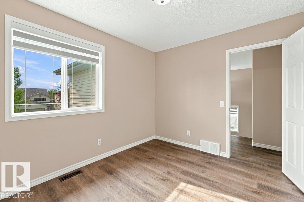 Room featuring wood-finish flooring, neutral wall paint, and white trim - 2811 33 Street, Edmonton, AB