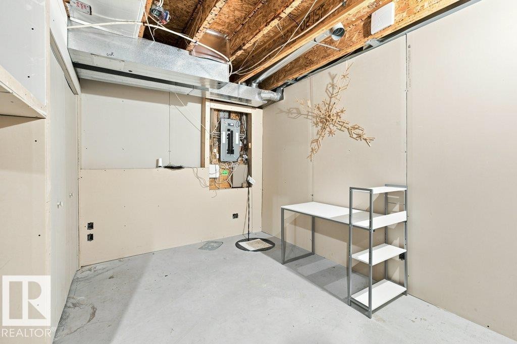 Unfinished interior space featuring exposed ceiling joists and ductwork, gypsum board wall panels, a concrete floor, and an exposed electrical panel - 2811 33 Street, Edmonton, AB