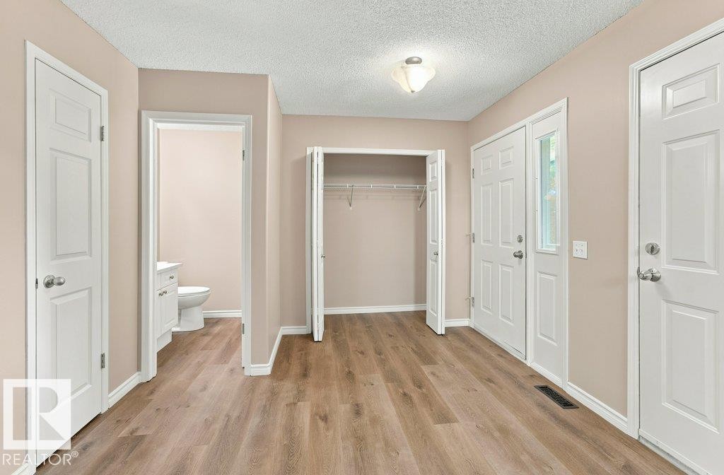 Entryway featuring wood-finish flooring, a double-door entry with a sidelight, and a built-in coat closet with bi-fold doors - 2811 33 Street, Edmonton, AB