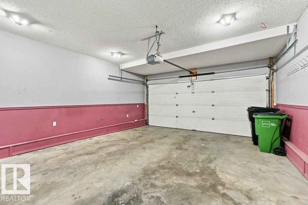 Concrete flooring garage with an automatic overhead door, overhead lighting, and two-tone wall treatment - 2811 33 Street, Edmonton, AB