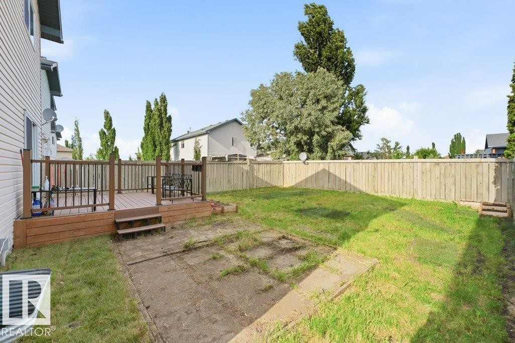 Expansive backyard featuring a wood deck with railings, a full privacy fence, and a concrete patio area - 2811 33 Street, Edmonton, AB