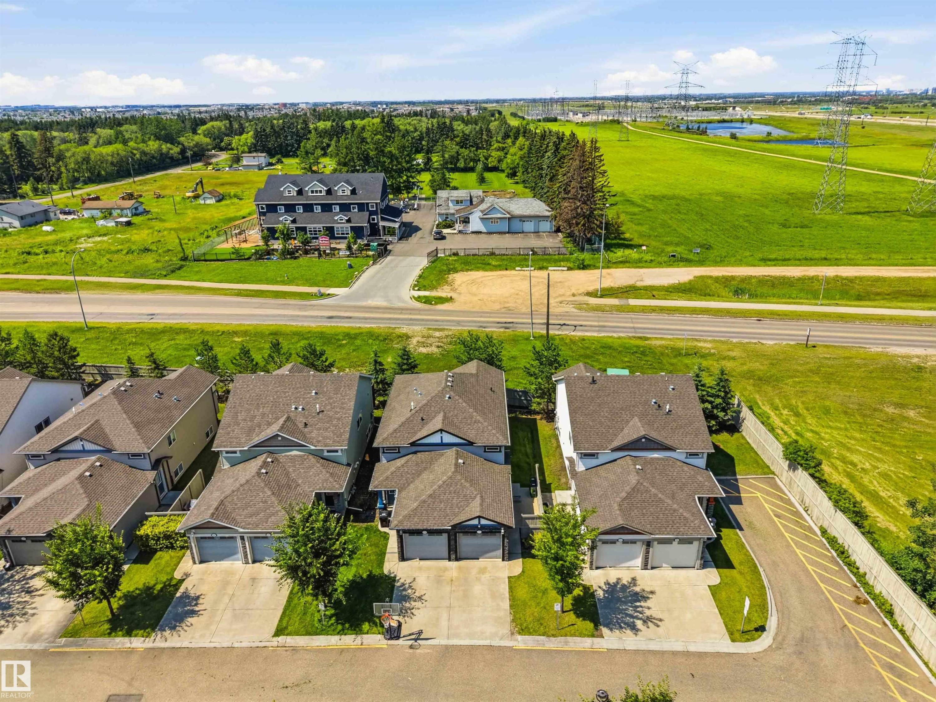 Residential streetscape featuring multiple two-story homes with attached garages, concrete driveways, and landscaped front yards - 24 6520 2 Avenue, Edmonton, AB