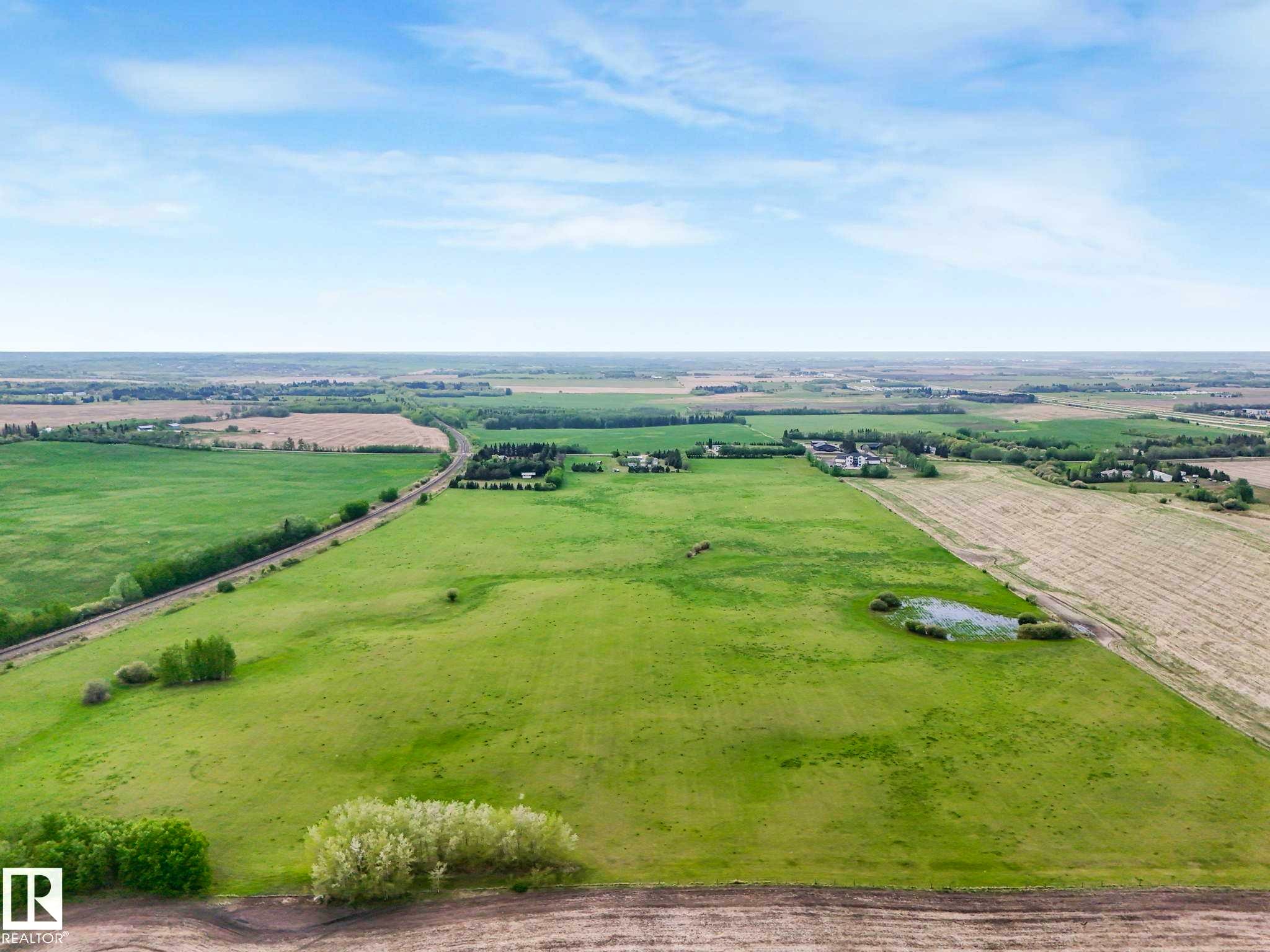 Expansive agricultural land featuring a verdant field, cultivated acreage, and natural wetland areas - 53133 Rge Road 223, Rural Strathcona County, AB - Outdoor With View
