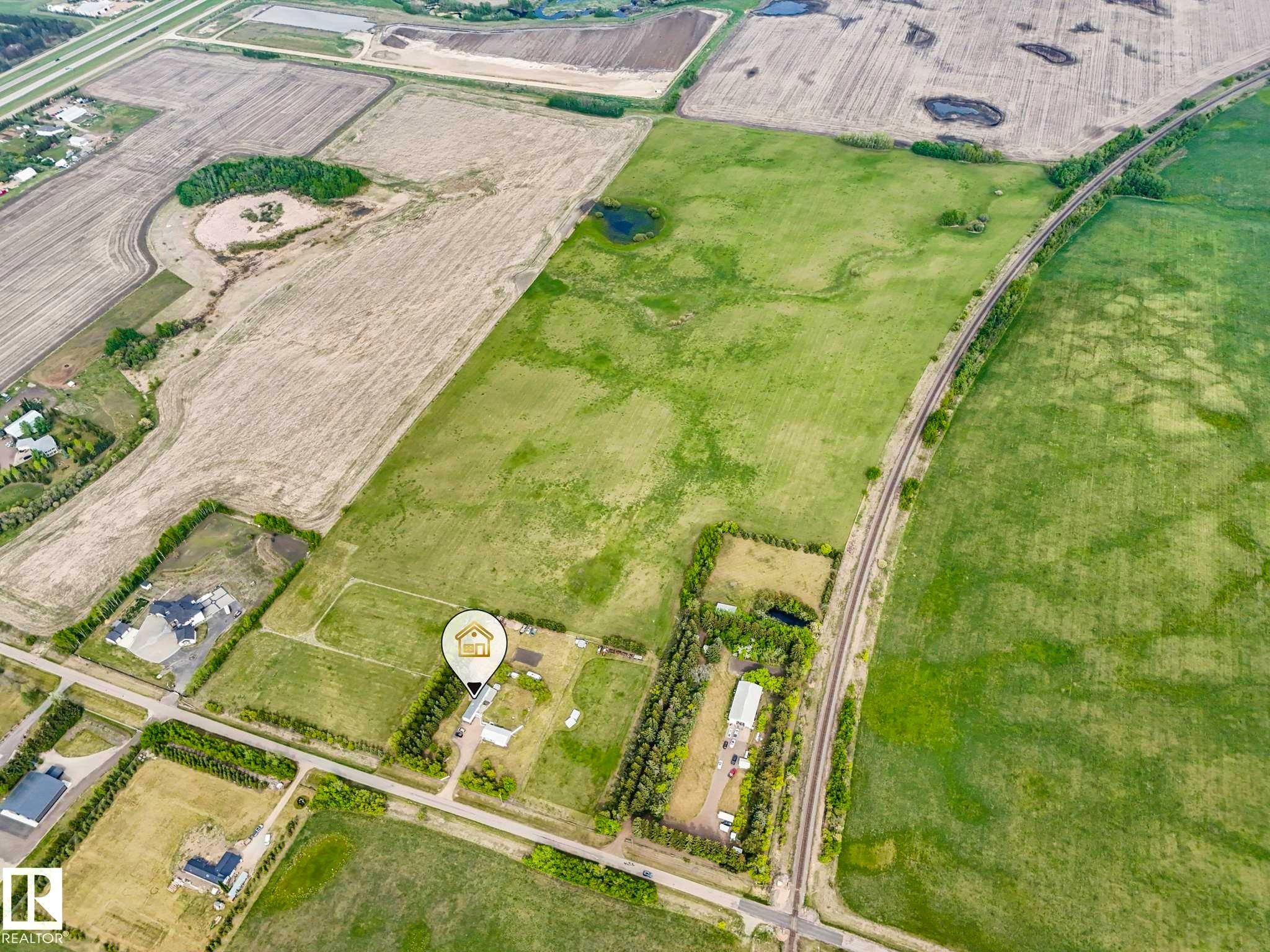Aerial view showcasing expansive land with varied terrain including cultivated fields and green pastures - 53133 Rge Road 223, Rural Strathcona County, AB - With View