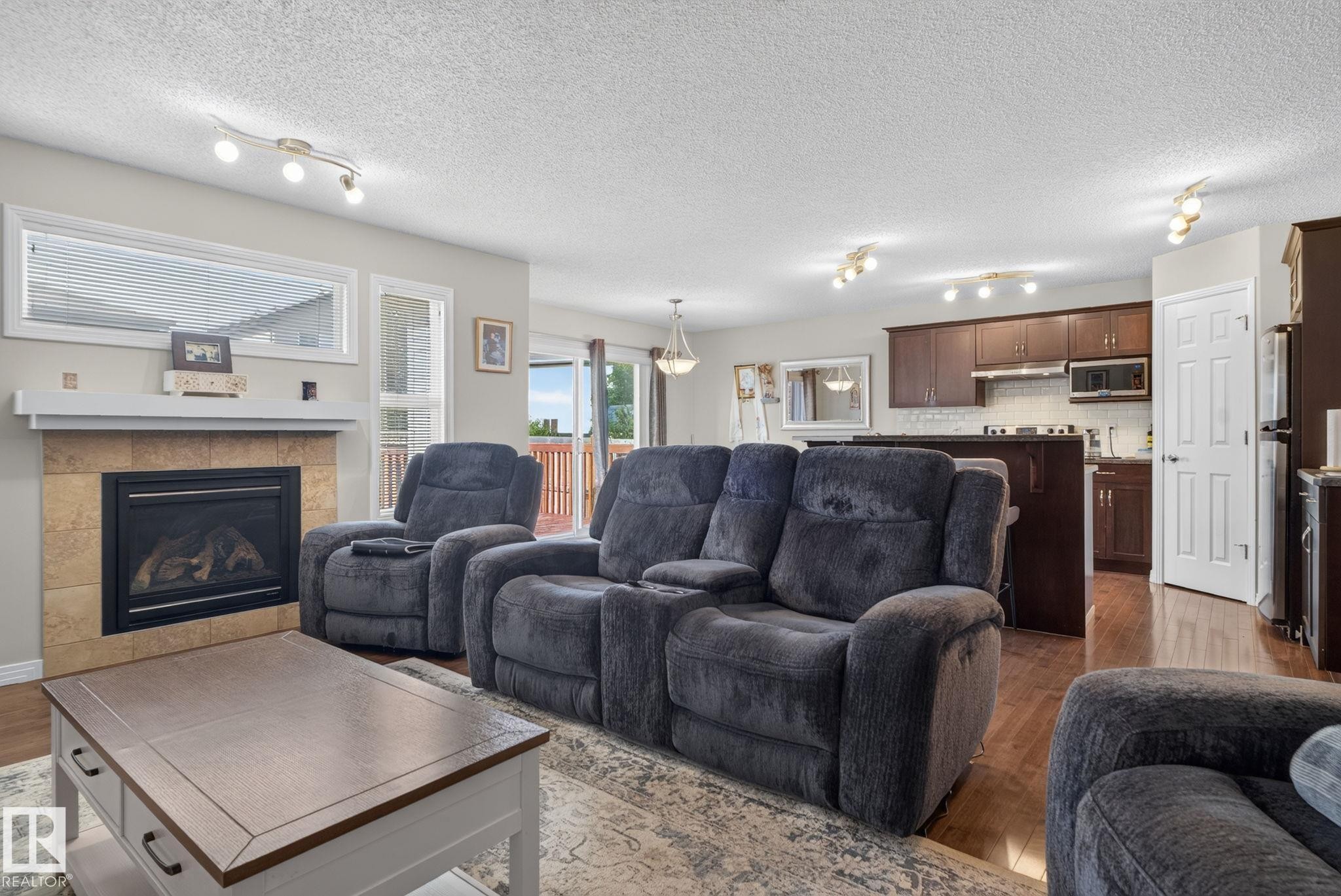 Open-concept living area featuring a tile-surround fireplace with a mantel - 7858 170A Avenue, Edmonton, AB