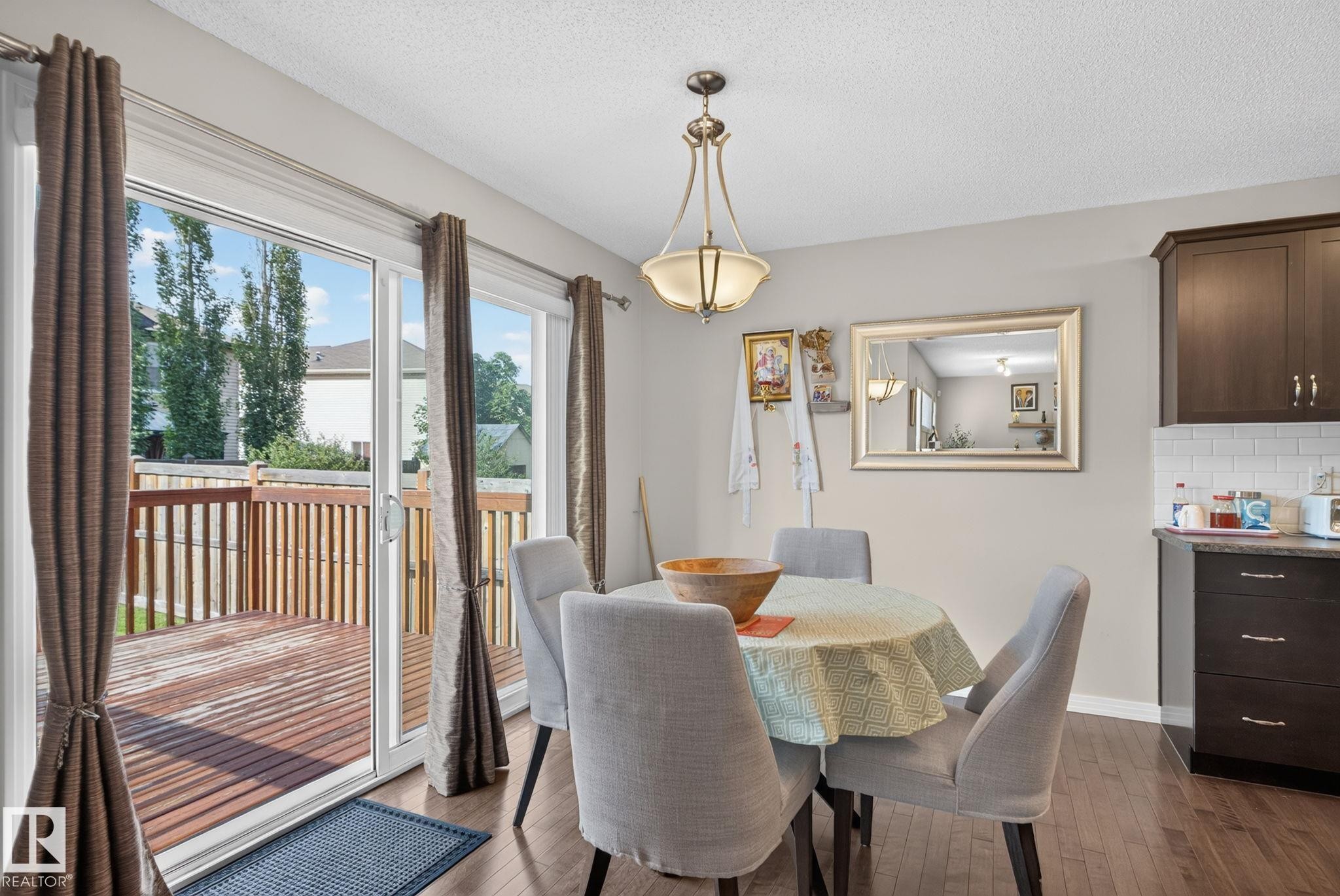 Dining area with wood-finish flooring and a central chandelier - 7858 170A Avenue, Edmonton, AB