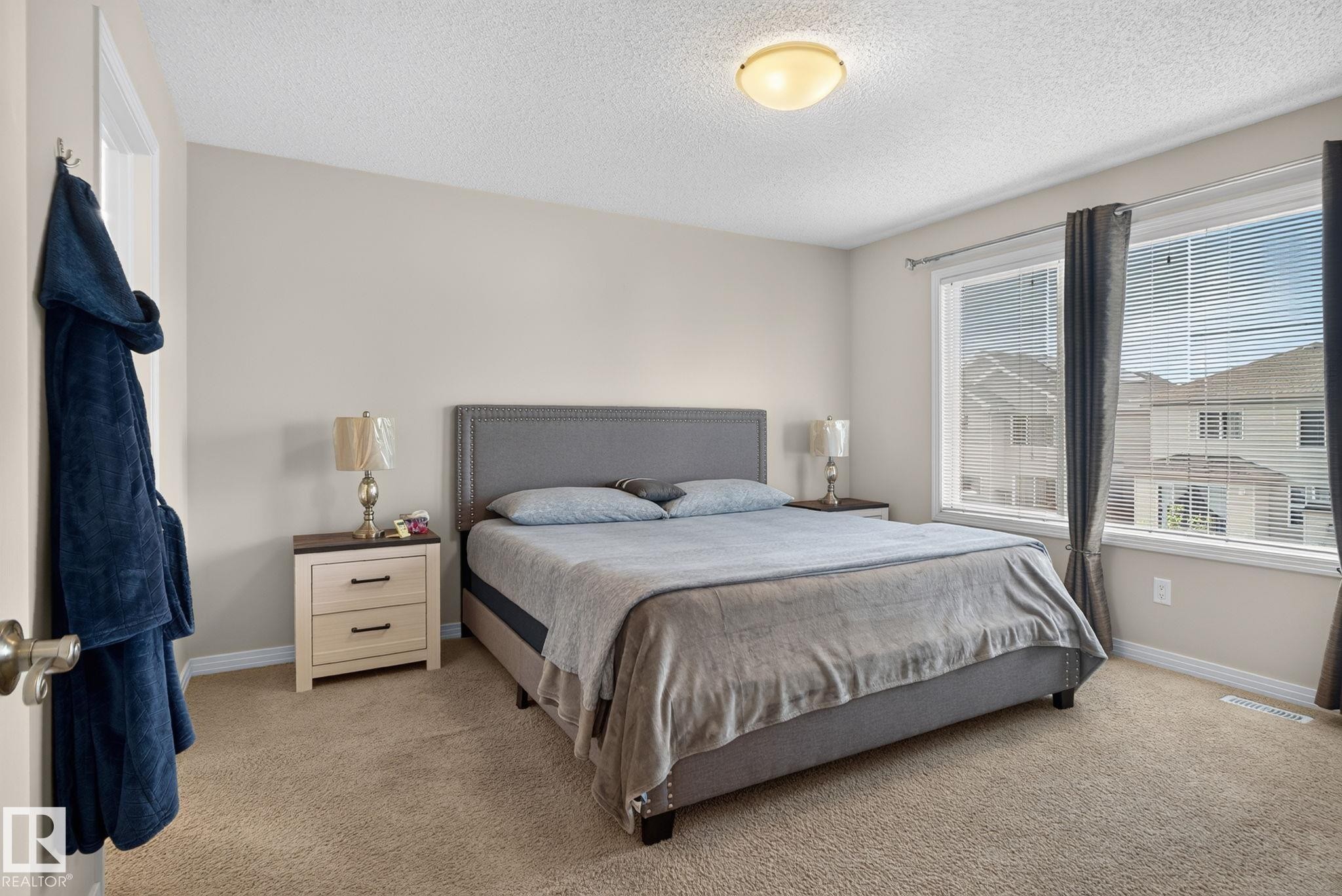 Carpeted bedroom featuring light neutral wall paint, white trim, and a ceiling-mounted light fixture - 7858 170A Avenue, Edmonton, AB
