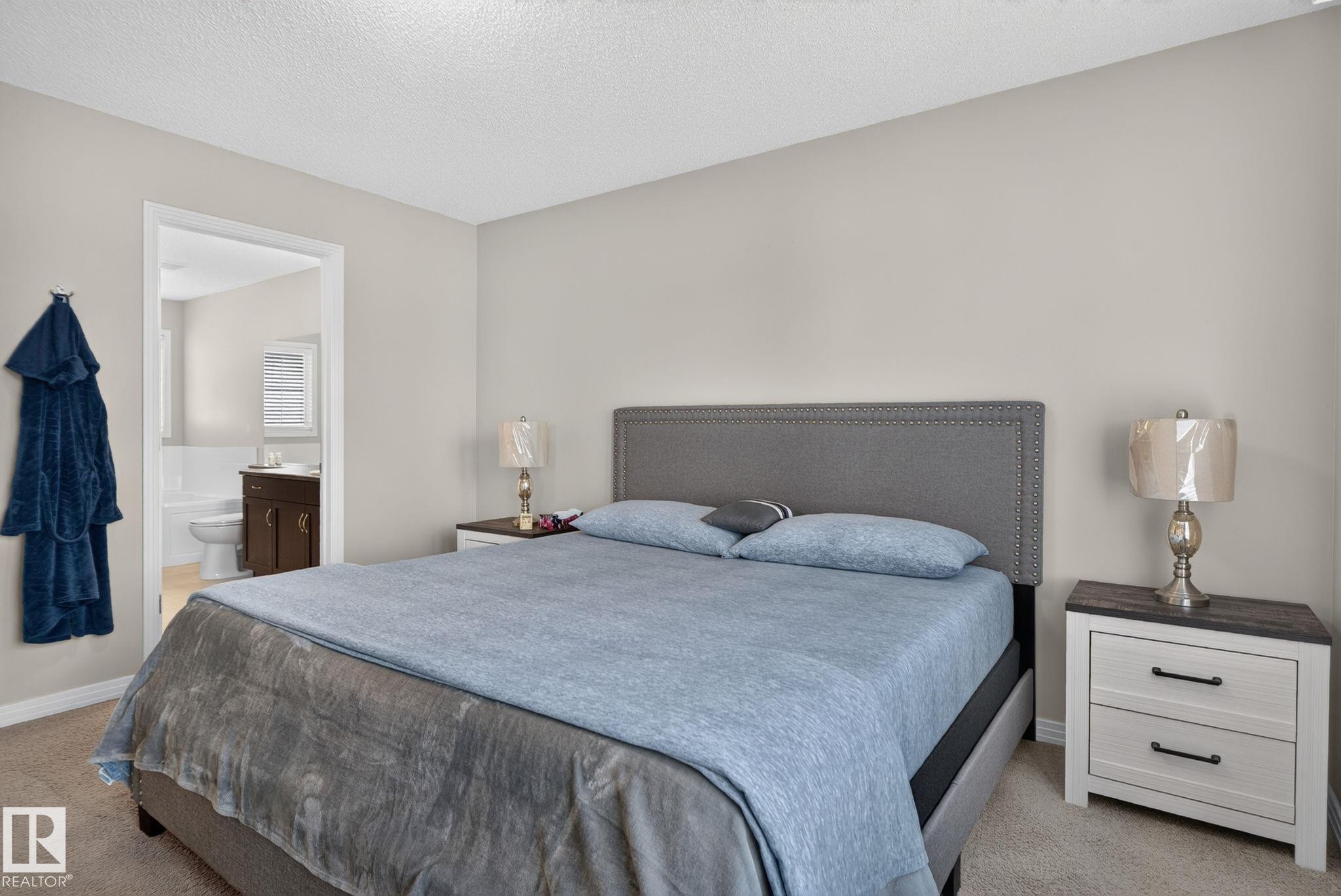 Carpeted bedroom with neutral wall tones and a textured headboard - 7858 170A Avenue, Edmonton, AB