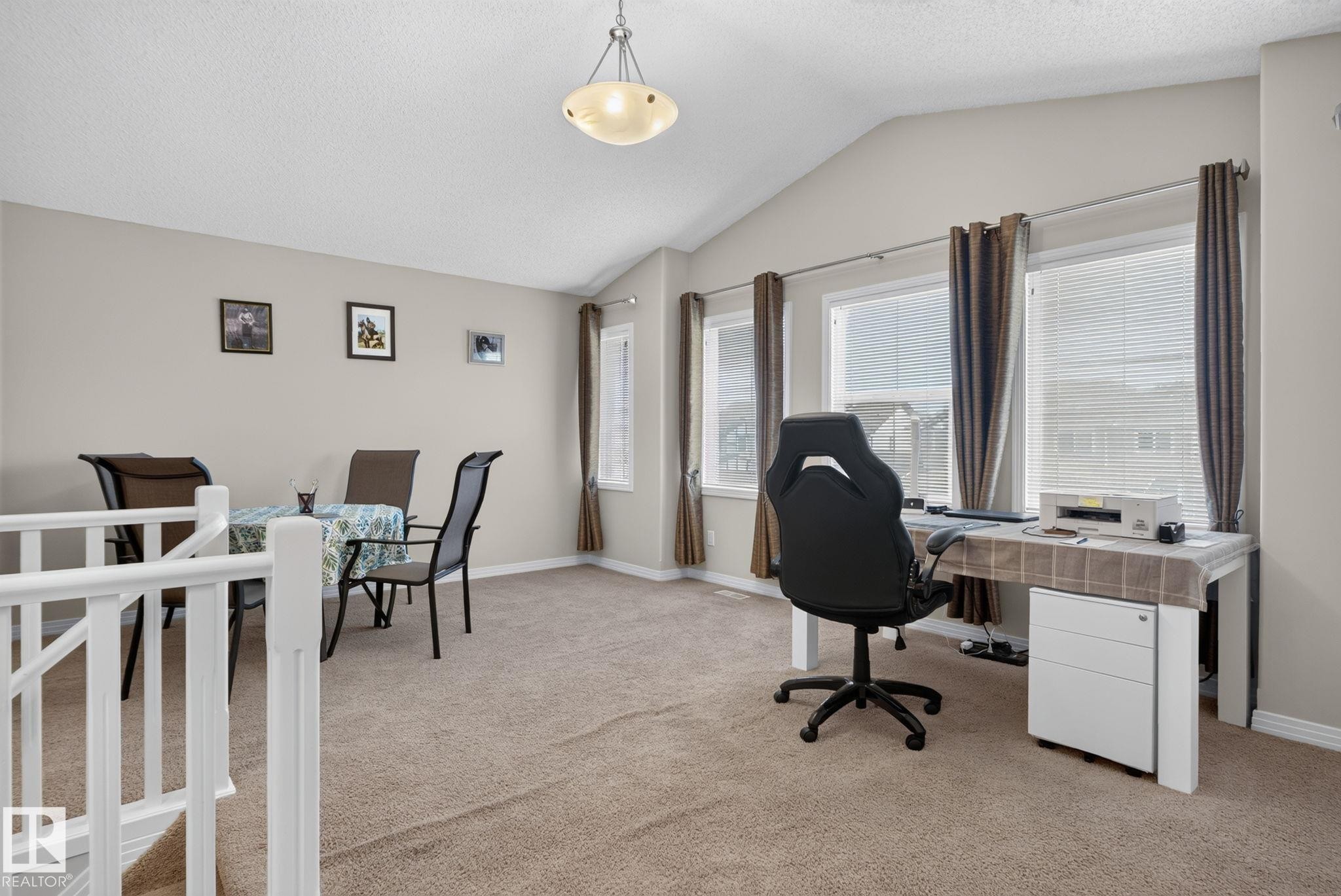 Expansive open-concept room featuring vaulted ceilings, light neutral wall tones, and carpet flooring - 7858 170A Avenue, Edmonton, AB