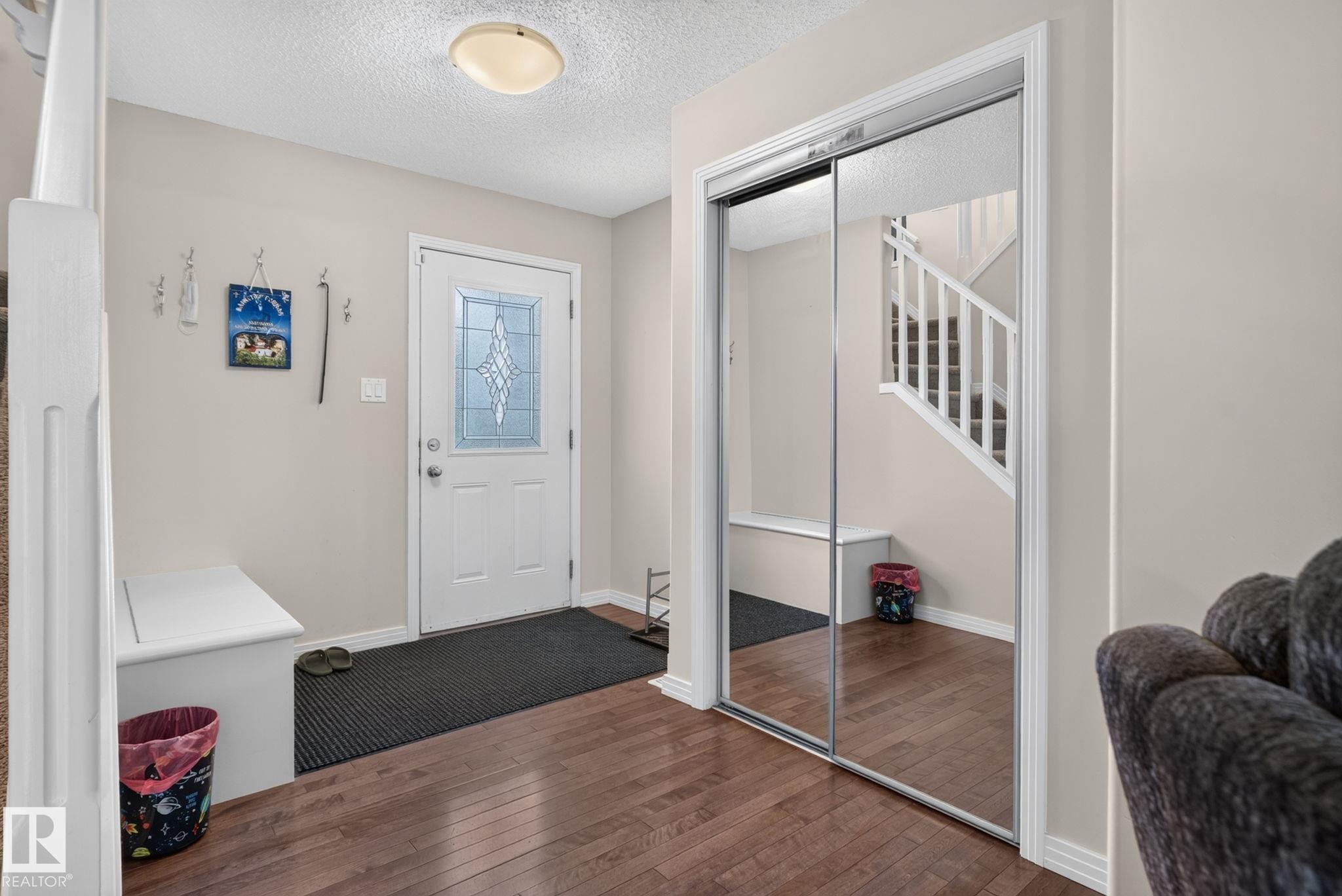 Entryway featuring wood-finish flooring and a white front door with decorative leaded glass - 7858 170A Avenue, Edmonton, AB