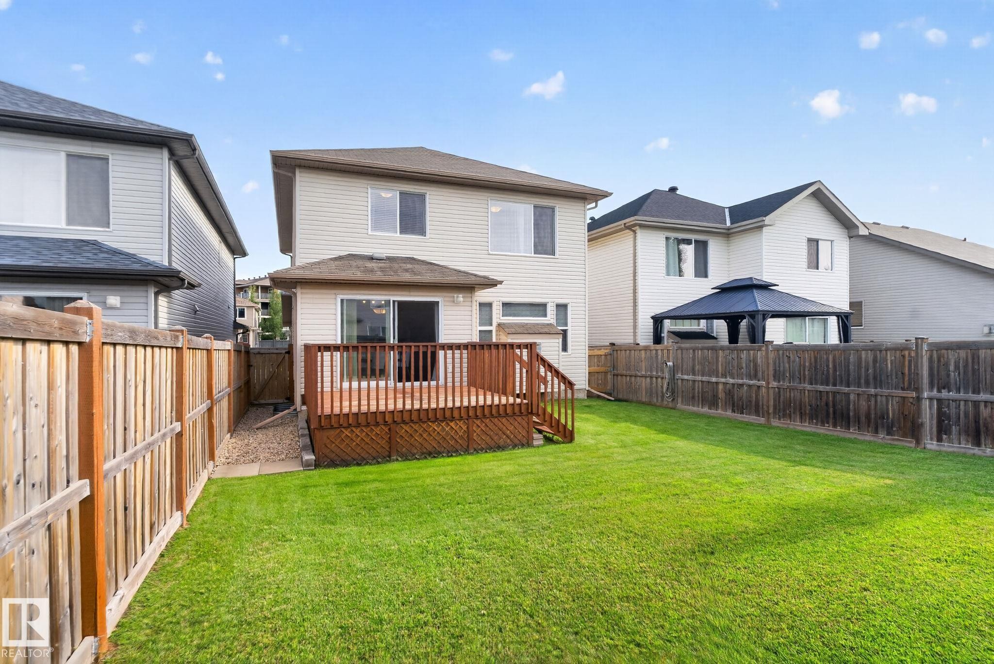 Expansive backyard featuring a manicured lawn, full wood fencing, and a private wooden deck - 7858 170A Avenue, Edmonton, AB