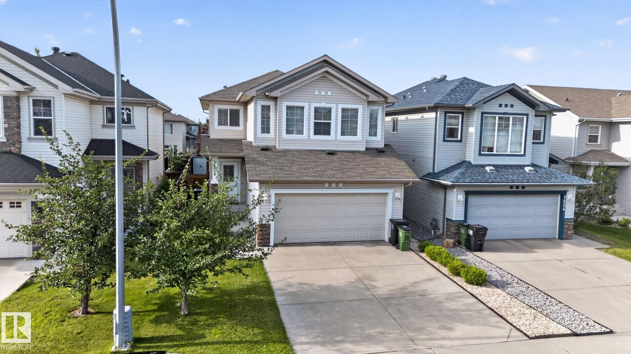 Two-story residential property featuring a light-colored siding exterior, an attached two-car garage, and a peaked roof - 7858 170A Avenue, Edmonton, AB