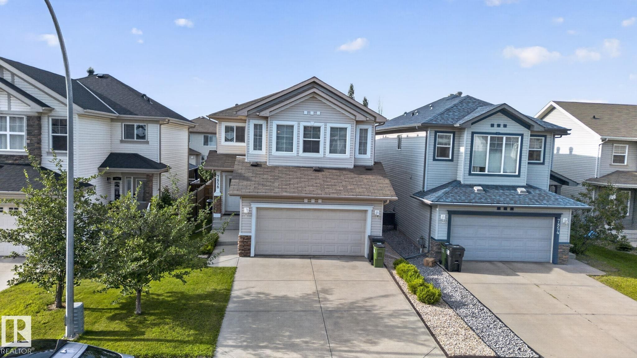 Two-story residence featuring light gray siding, a two-car garage, and a concrete driveway - 7858 170A Avenue, Edmonton, AB