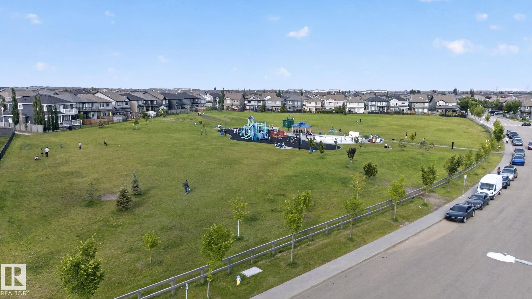 Expansive green space featuring a playground with multiple structures, surrounded by residential properties - 7858 170A Avenue, Edmonton, AB