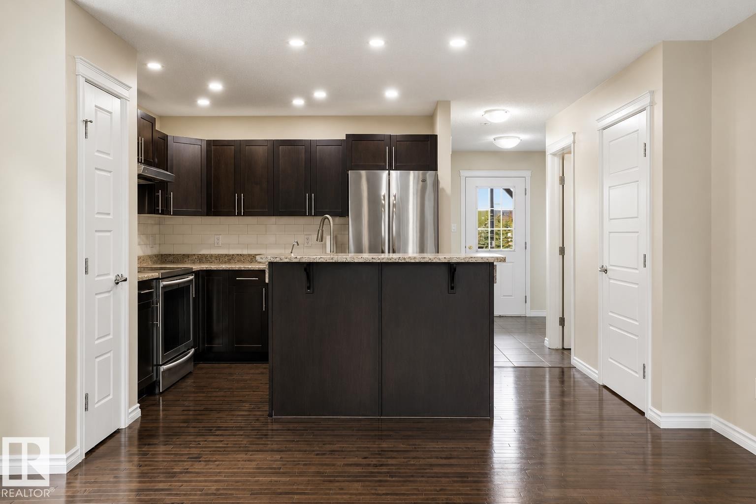 Open-concept kitchen featuring dark wood cabinetry, stainless steel appliances, and a central island with a granite-style countertop - 445 Watt Boulevard Sw, Edmonton, AB - Indoor Photo Showing Kitchen With Upgraded Kitchen