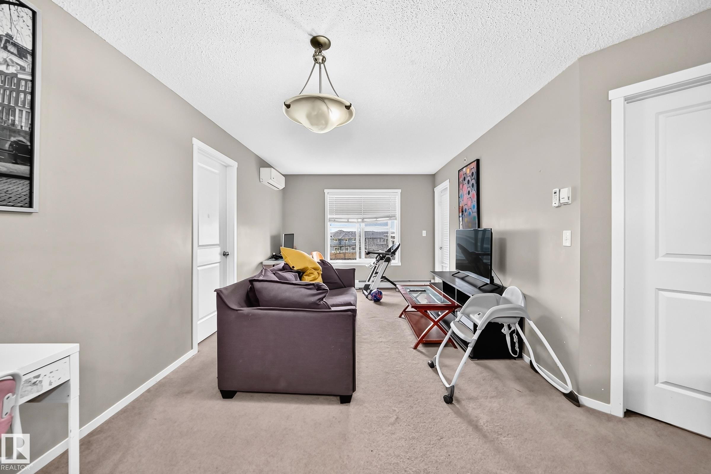 Carpeted living space with neutral painted walls and a textured ceiling - #417 1510 Watt Dr Sw, Edmonton, AB - Indoor