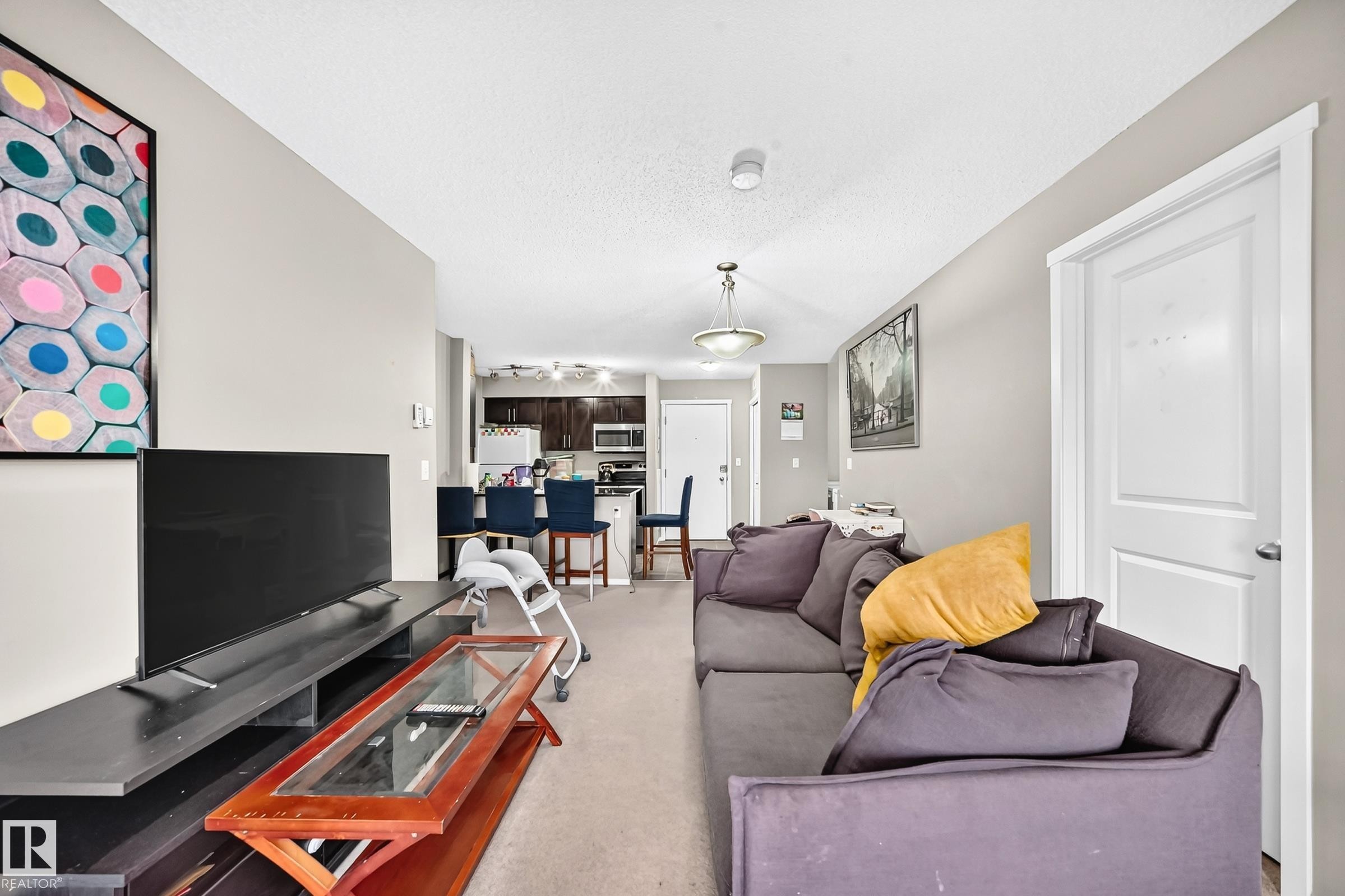 Open-concept living area with neutral wall tones and carpet flooring - #417 1510 Watt Dr Sw, Edmonton, AB - Indoor Photo Showing Living Room