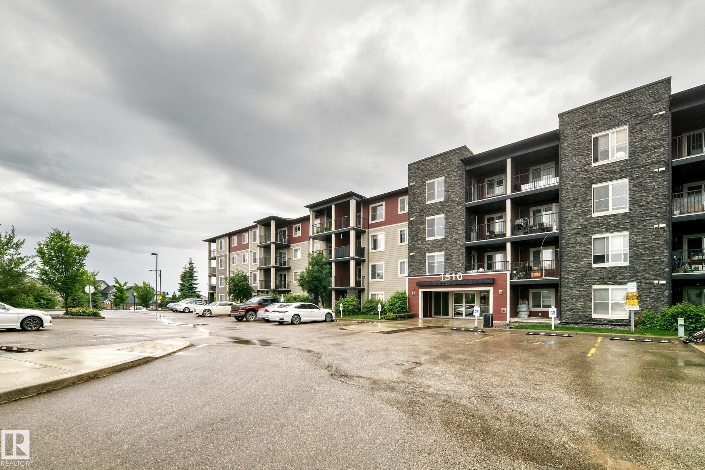 Multi-story residential building featuring dark stone facade accents and lighter-toned siding - #417 1510 Watt Dr Sw, Edmonton, AB - Outdoor With Balcony With Facade
